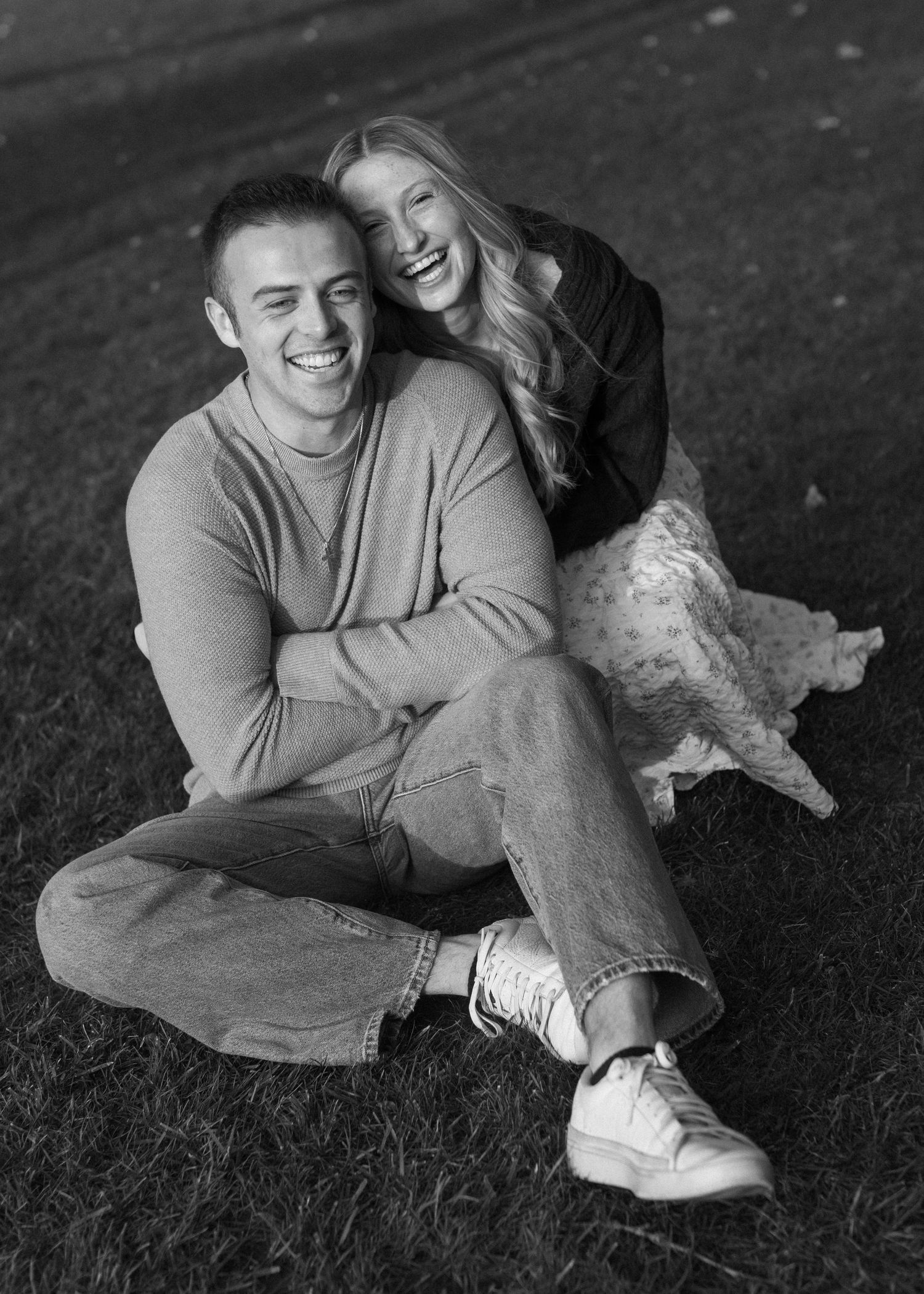 Black and white photos of couple lounging on grass in casual wear.