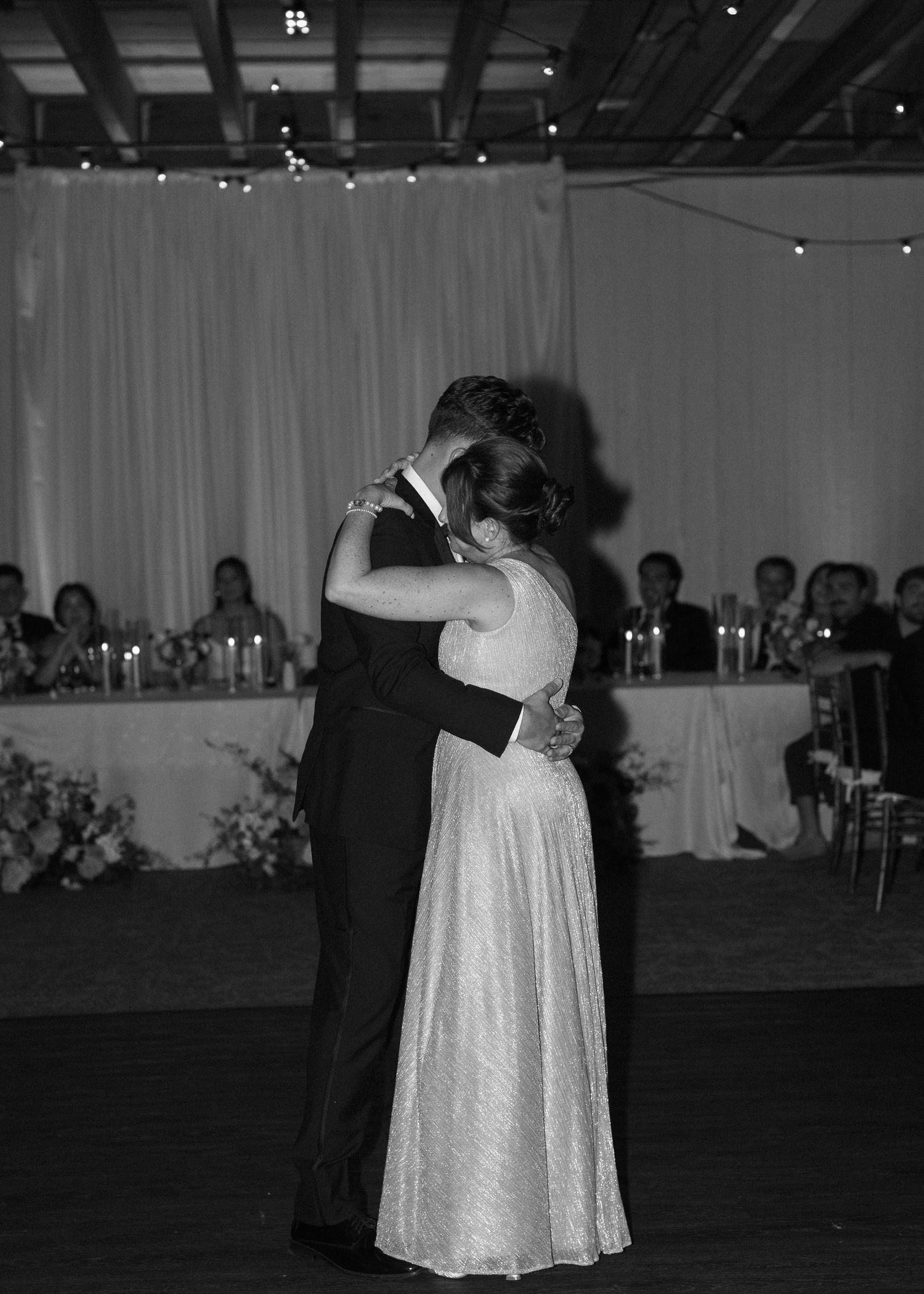 A black and white photo of a couple sharing their first dance at their wedding reception.