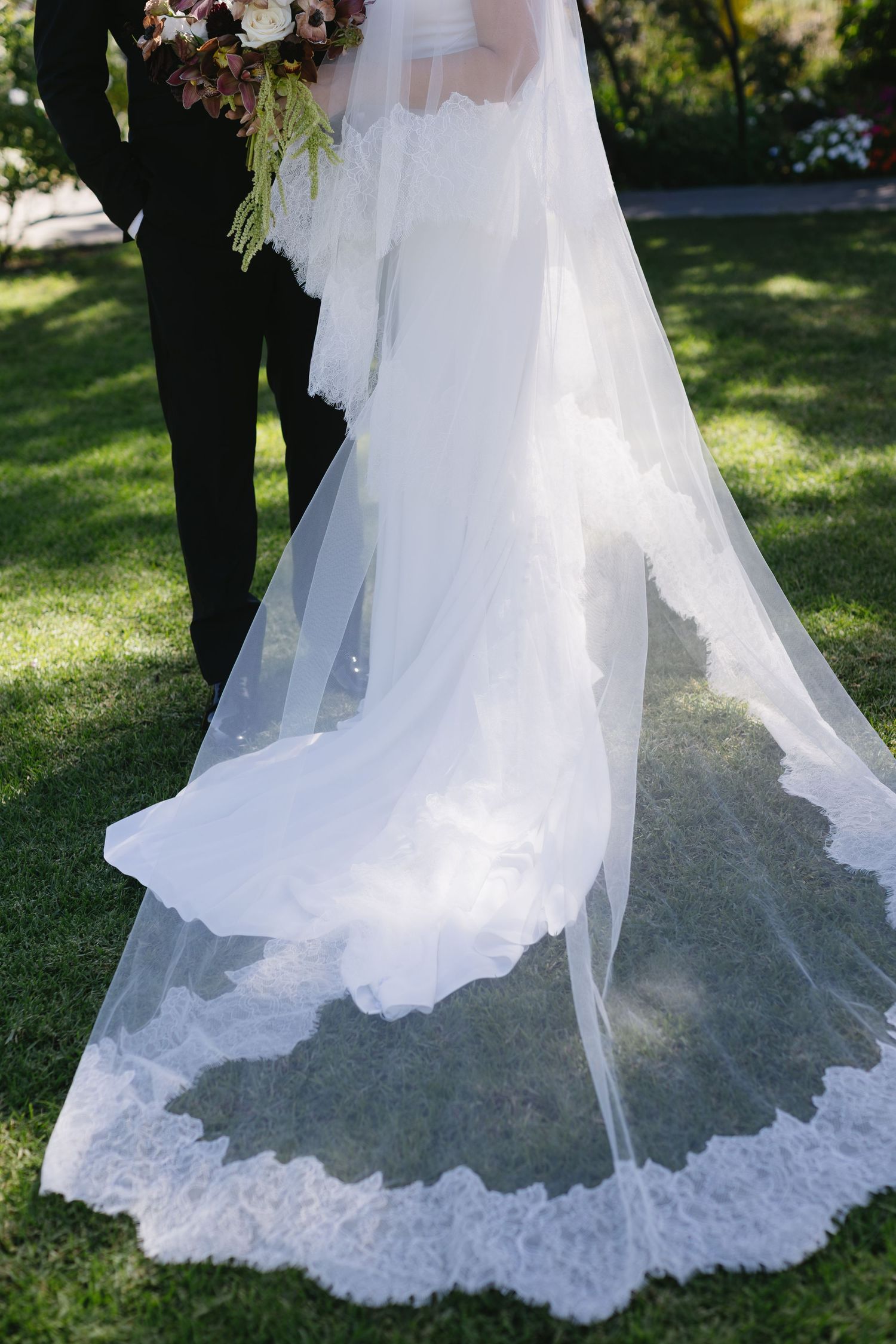 Detailed shots of a white wedding dress train with intricate lace details on grass.