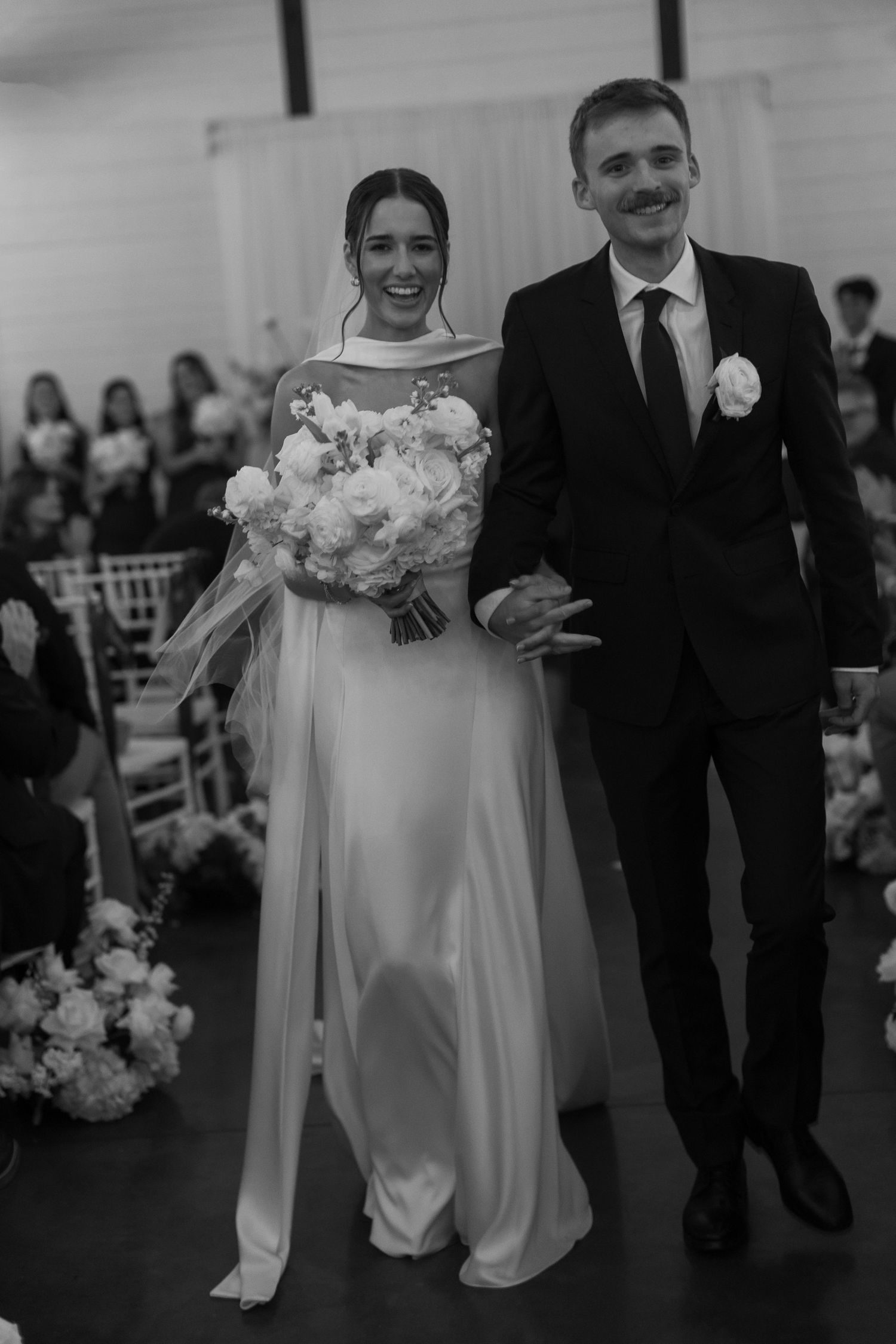 Newlyweds walk down the aisle together after their ceremony surrounded by floral decorations.