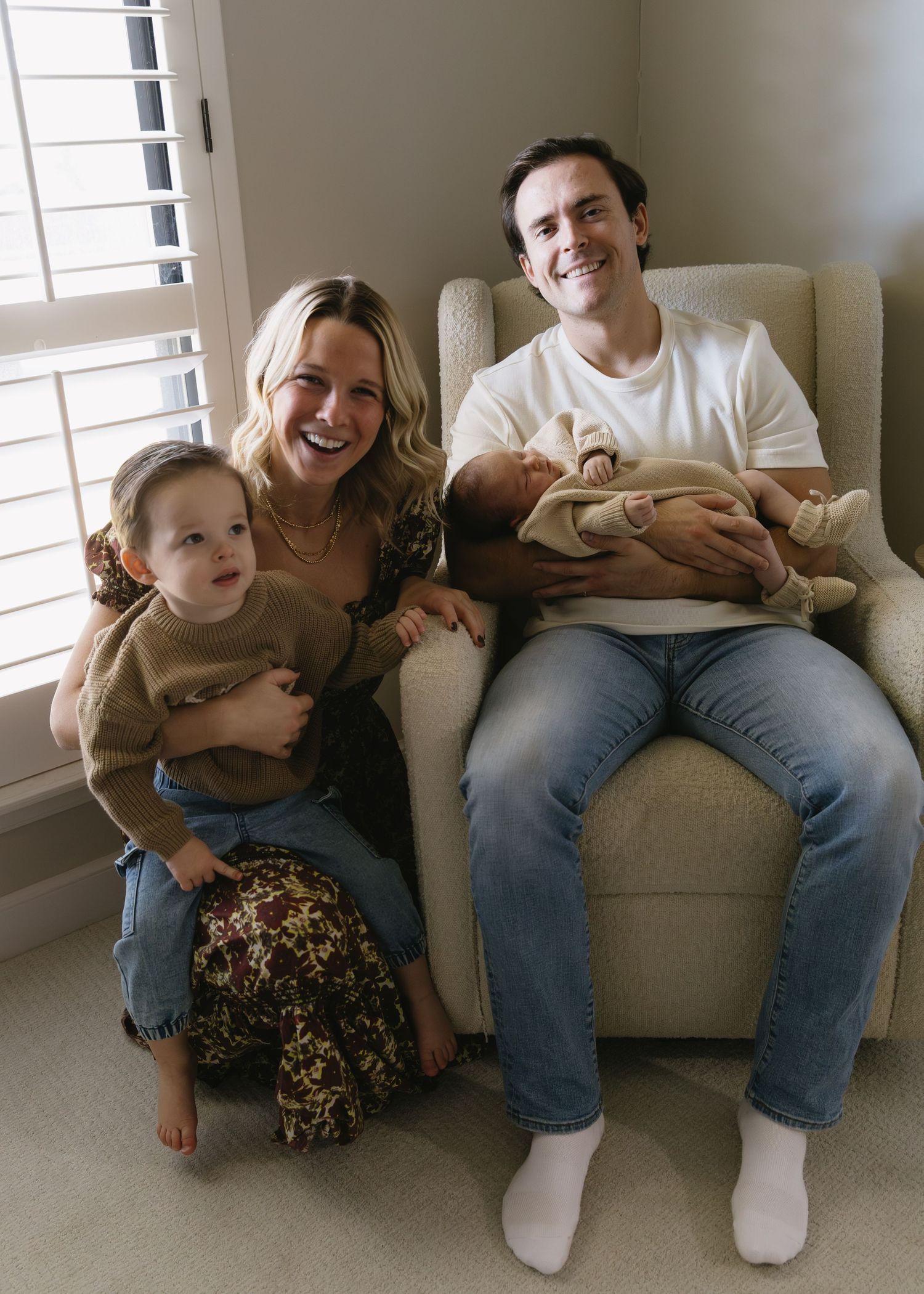 Family shares joyful moments together on a cozy gray couch in casual attire.