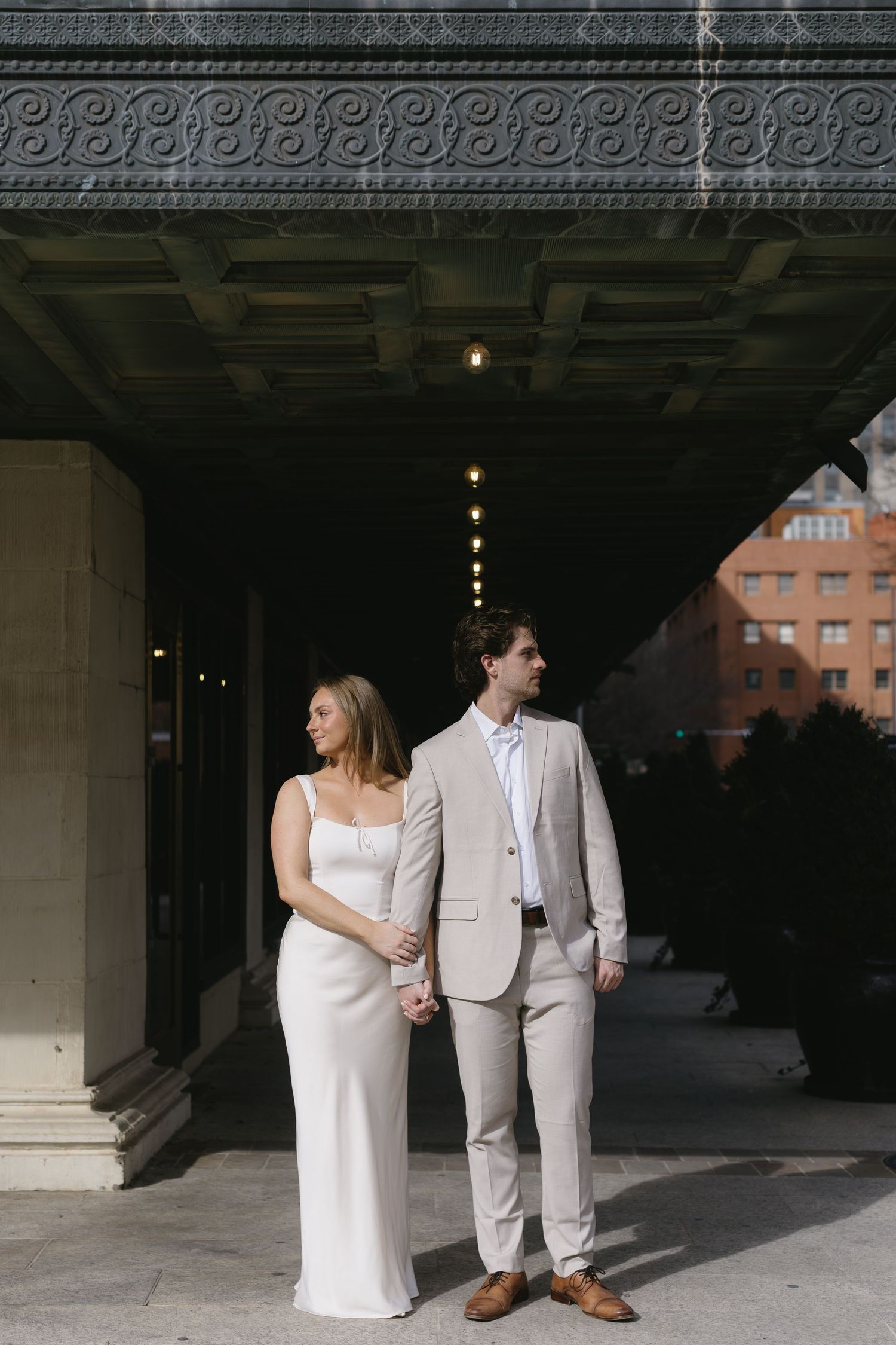 A bride and groom share intimate moments under a grand architectural archway.