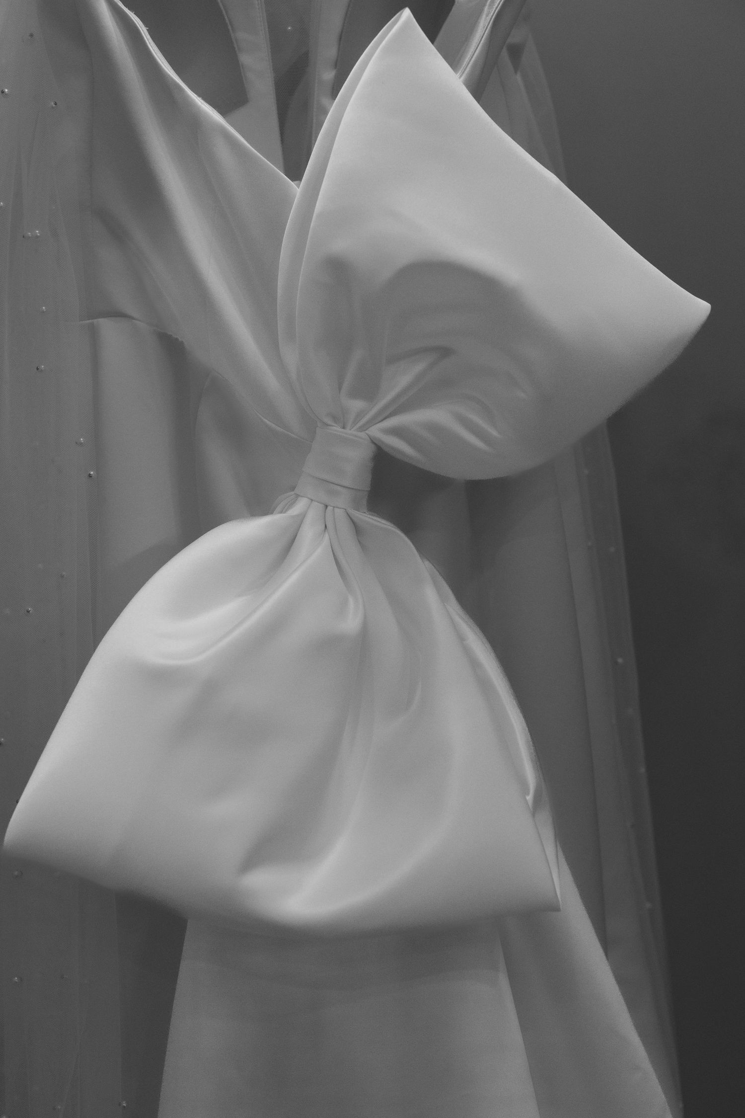 Close-up of an elegant white satin bow detail on a wedding dress.