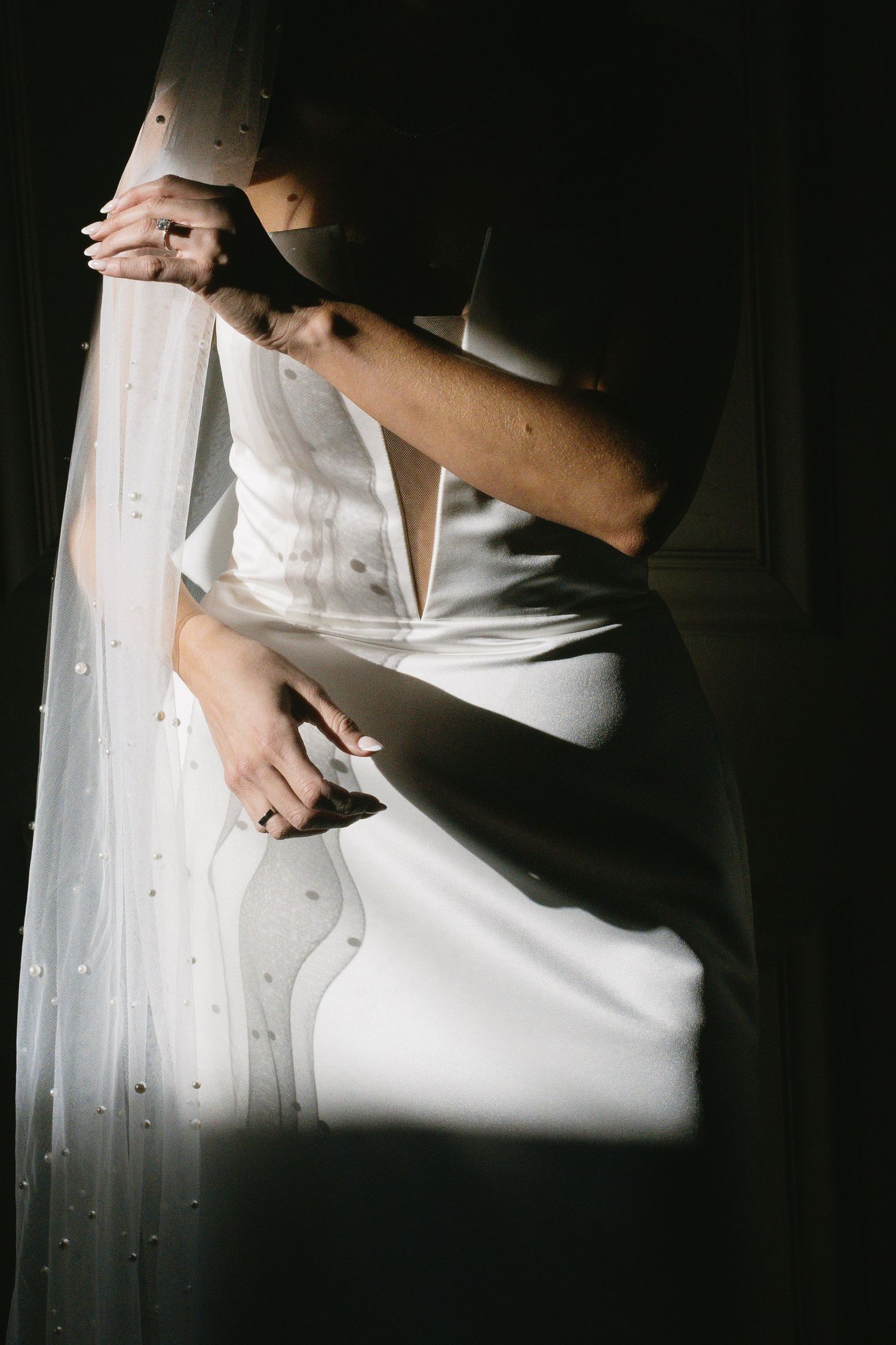 A close-up view of white satin fabric with dramatic shadows and lighting.