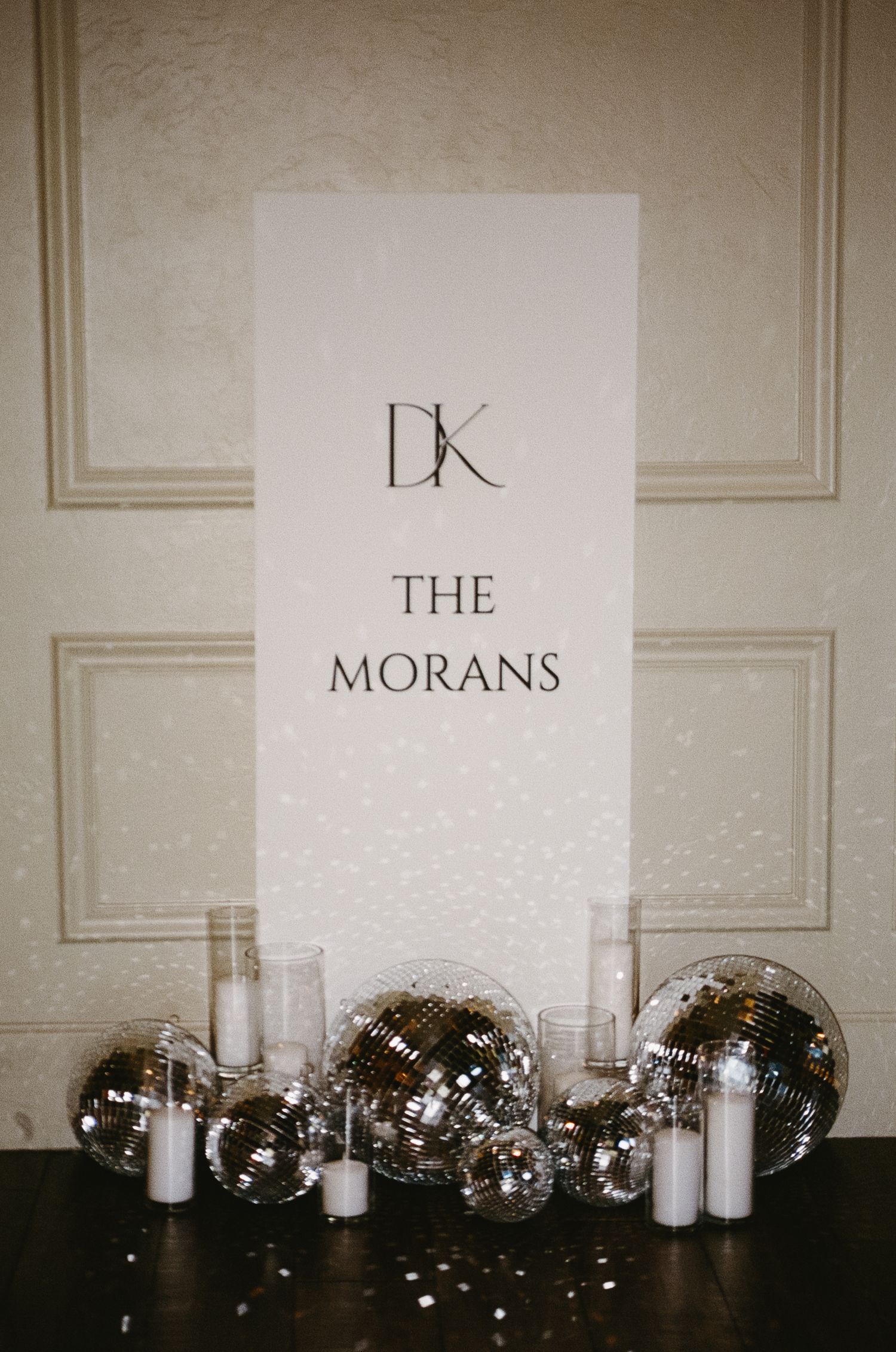 Disco balls and white candles line up against a white wall with text displays reading 'THE MORAINS'.