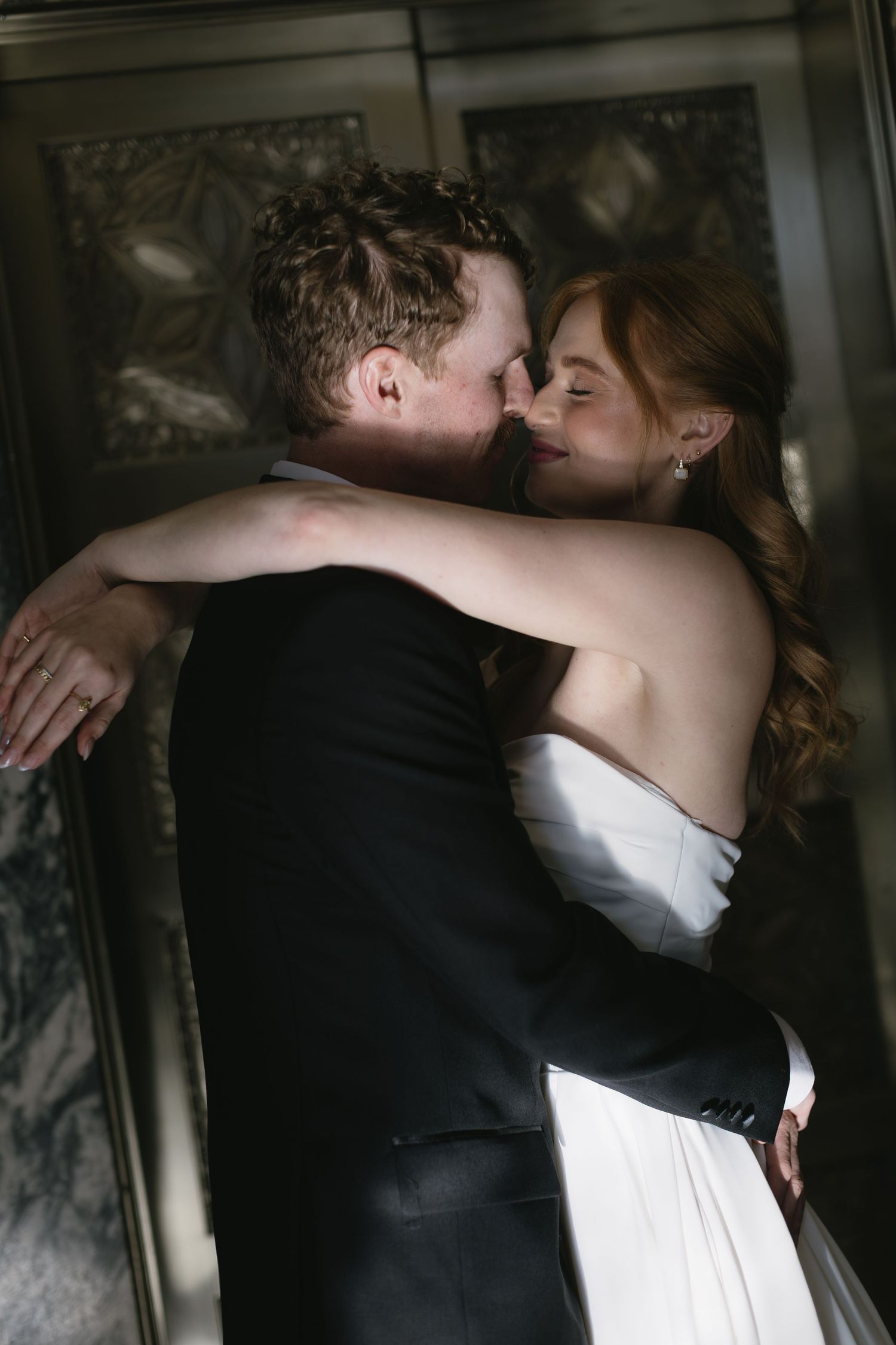 Romantic wedding couple embraces in dramatic lighting during their first look moment.