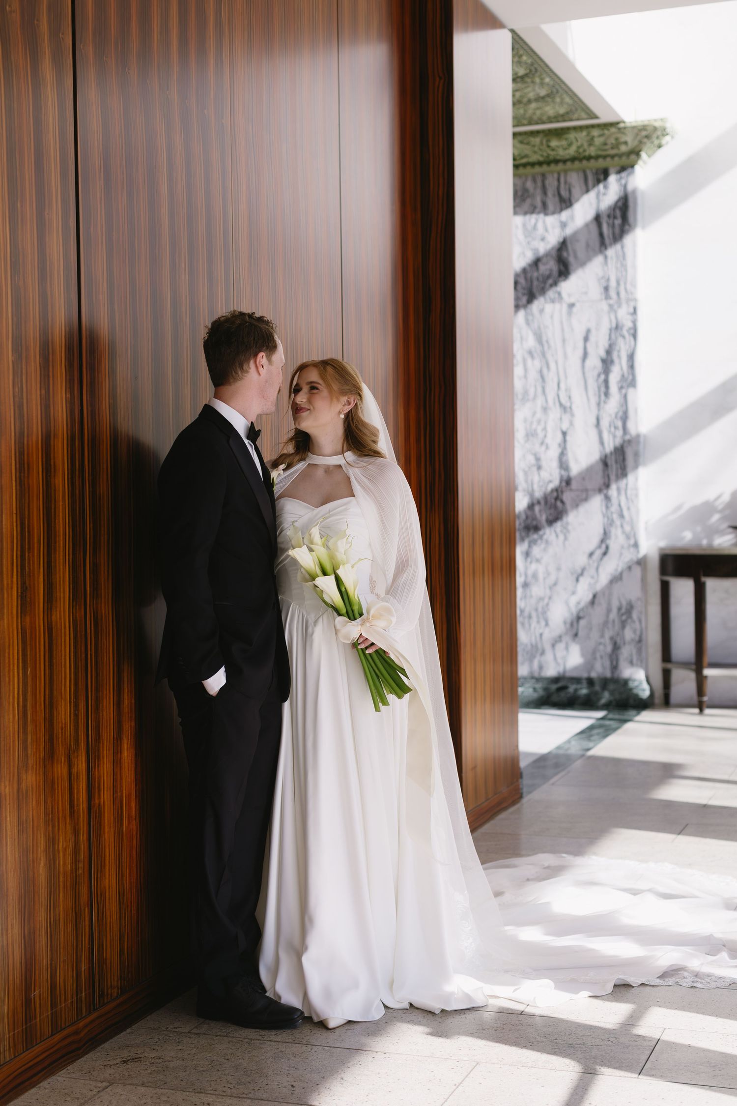 Wedding couple sharing intimate moments against wood paneled walls with dramatic lighting.