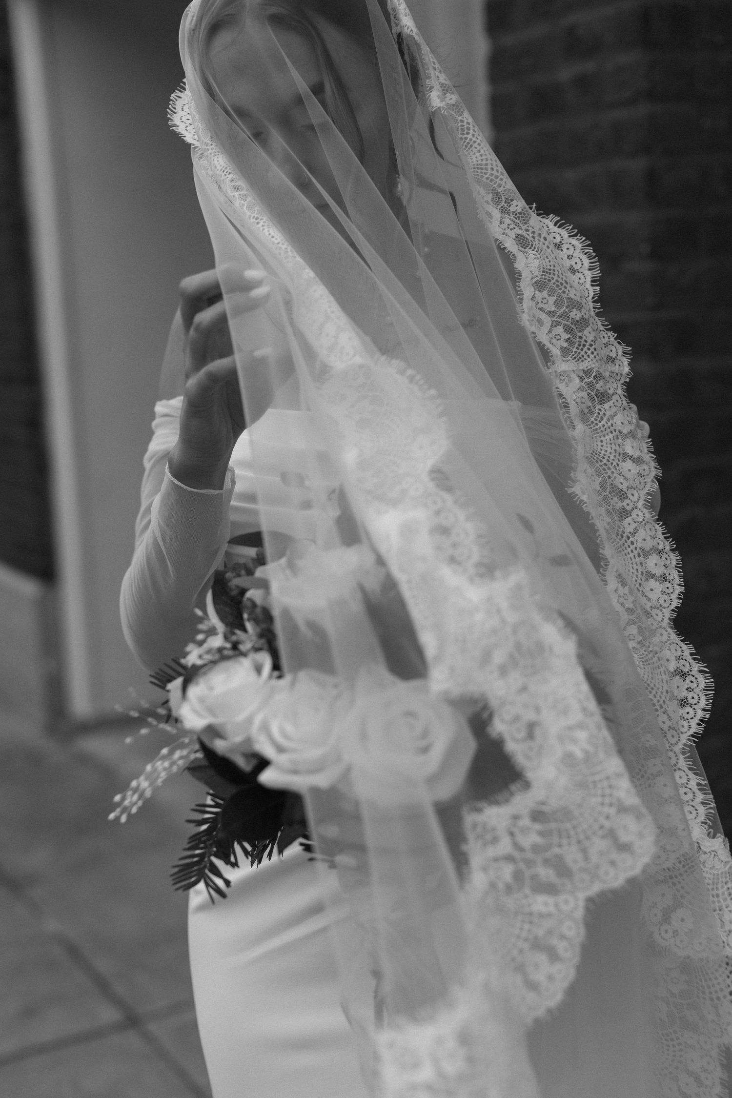 Delicate lace veil detail with floral embellishments in black and white photography.