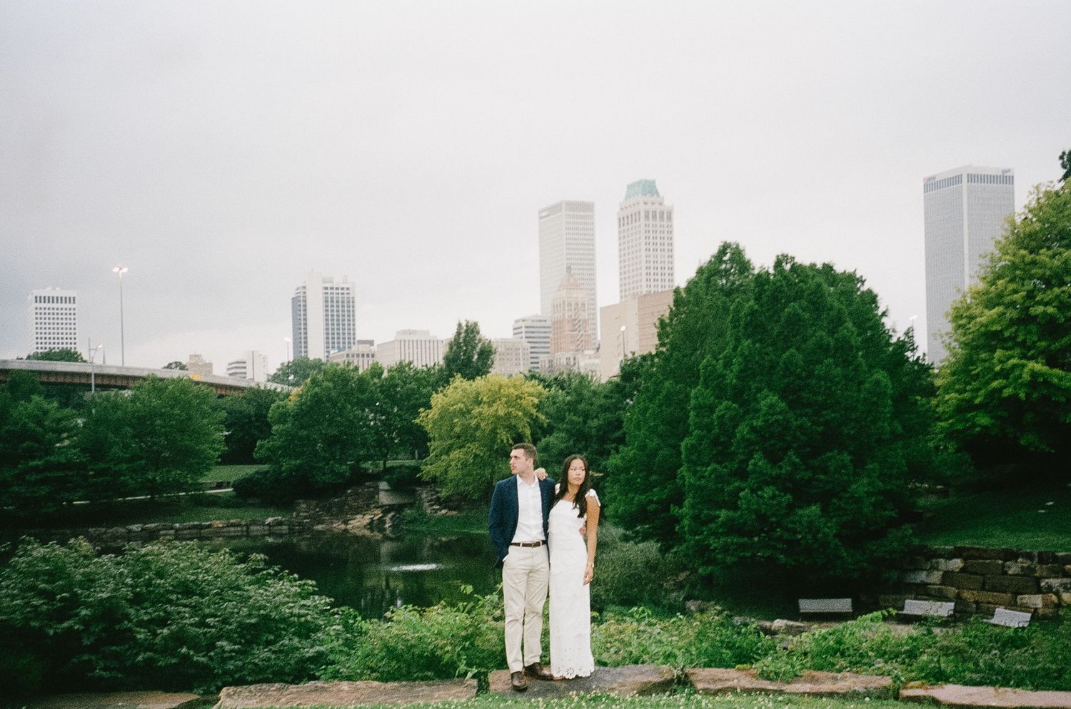 New York City skyline view with Twin Towers visible through green park trees and pathways.