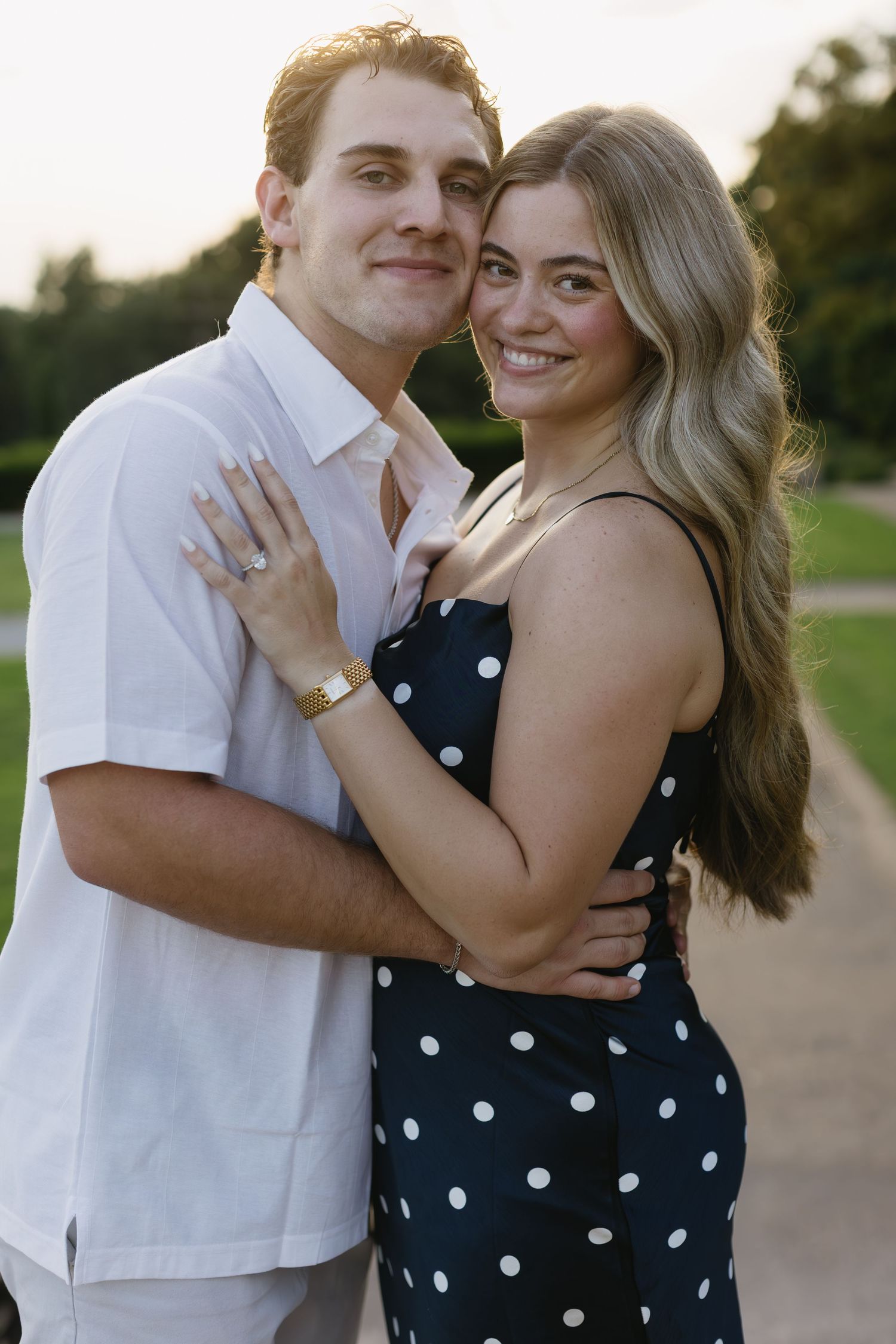 Happy couple poses together outdoors, wearing coordinating white and polka dot outfits while embracing.
