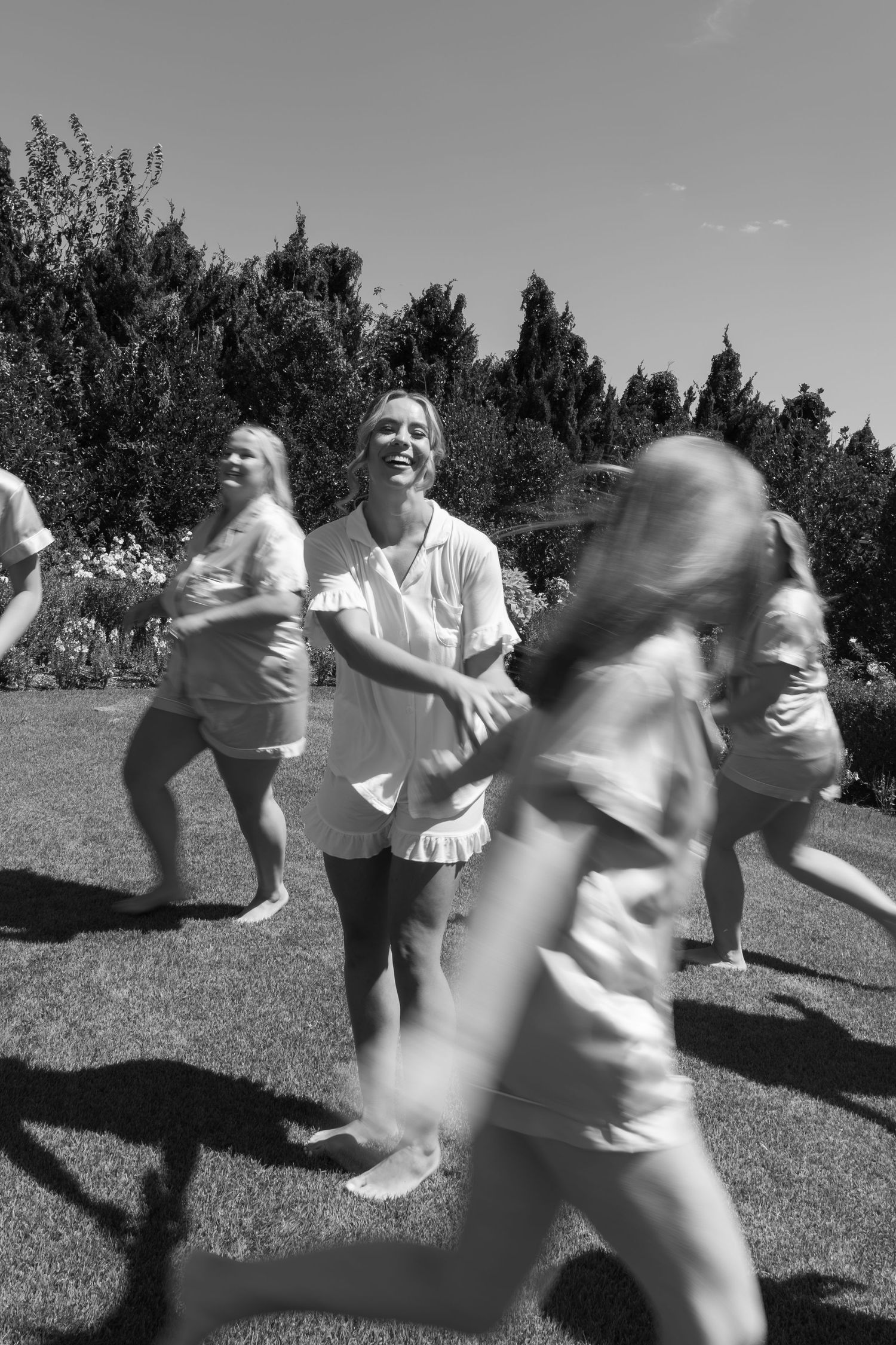 Black and white photo of people dancing and moving outdoors in a joyful celebration.