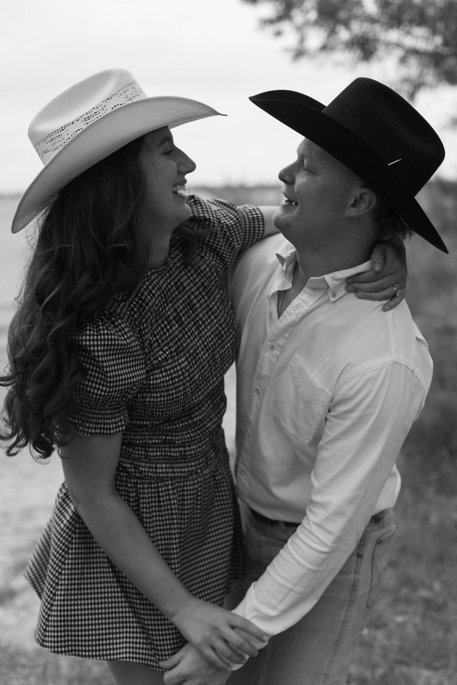 Couple in western hats sharing romantic moments in black and white photography.