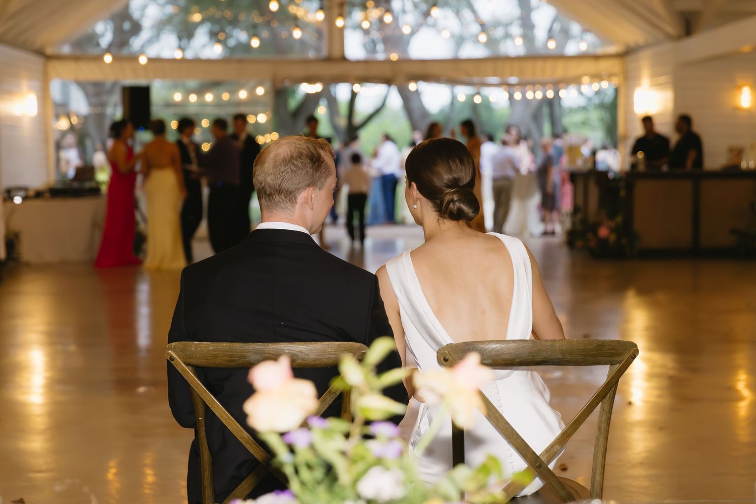 Wedding reception venue interior with string lights and elegant table settings.