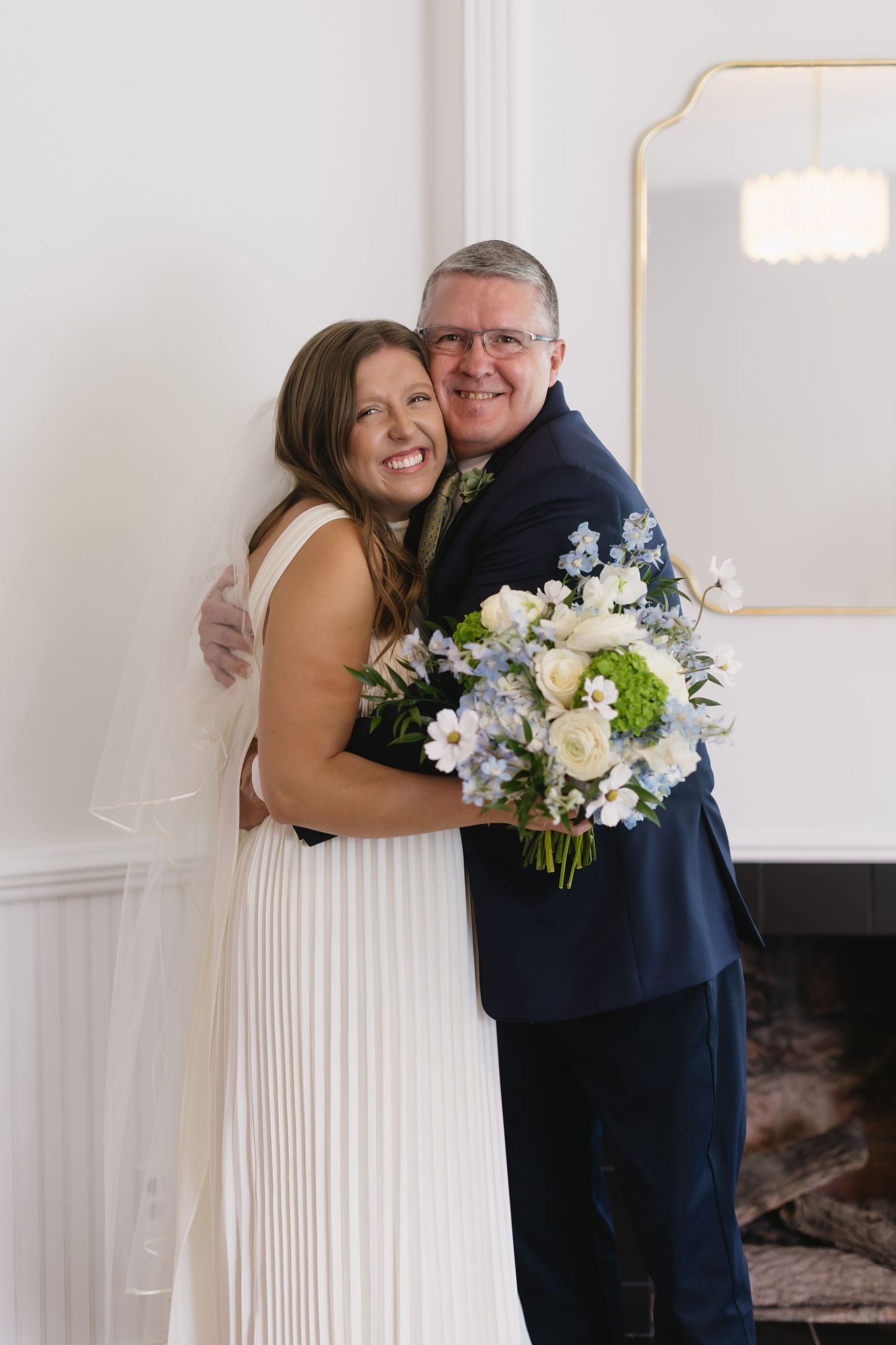 Wedding day first look between couple wearing navy suit and white dress with beautiful floral bouquet.