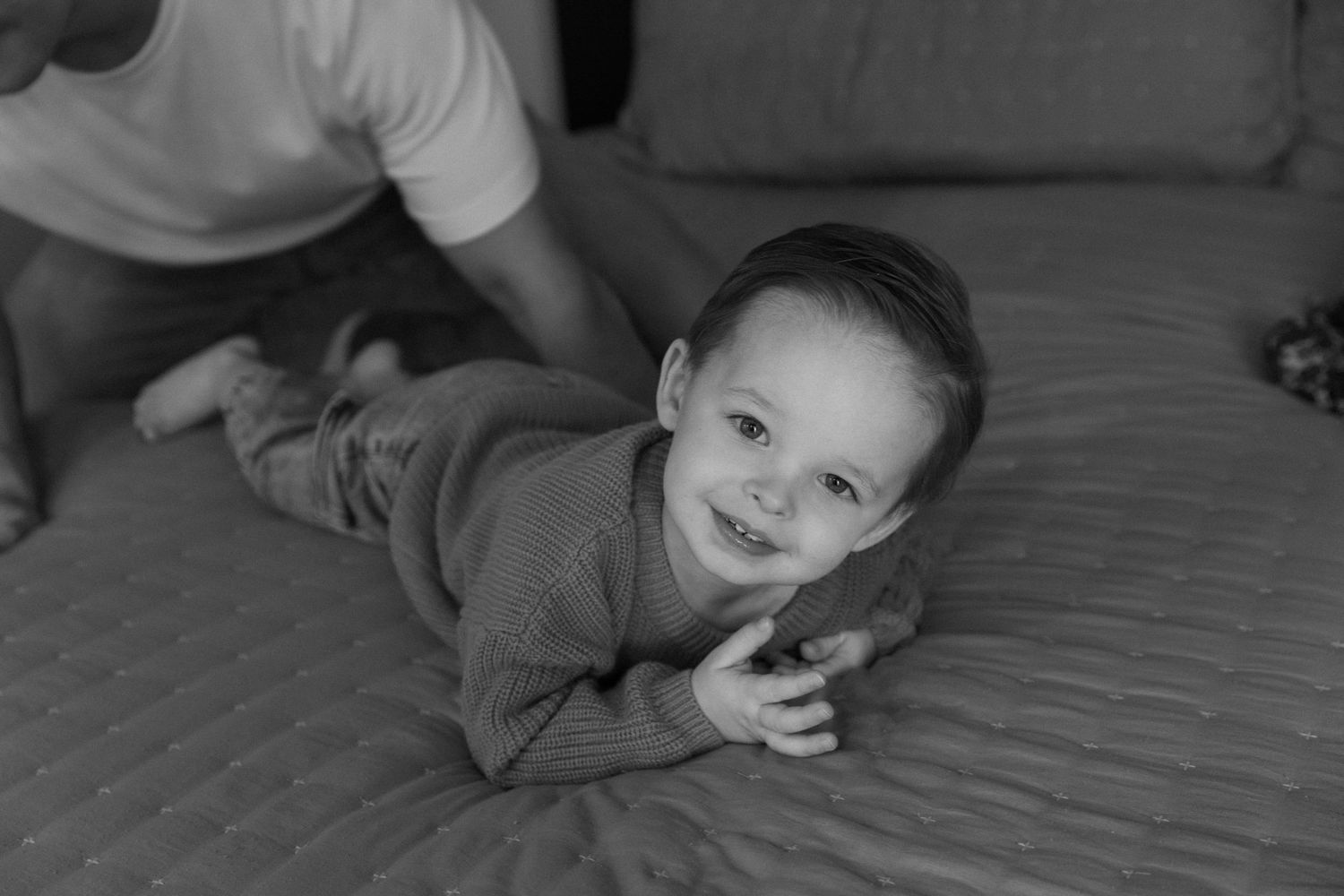 Black and white photo sequence showing a toddler playing and making different expressions on a hardwood floor.