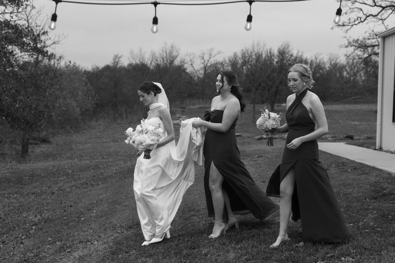 Wedding party relaxes outdoors under string lights during an autumn celebration.