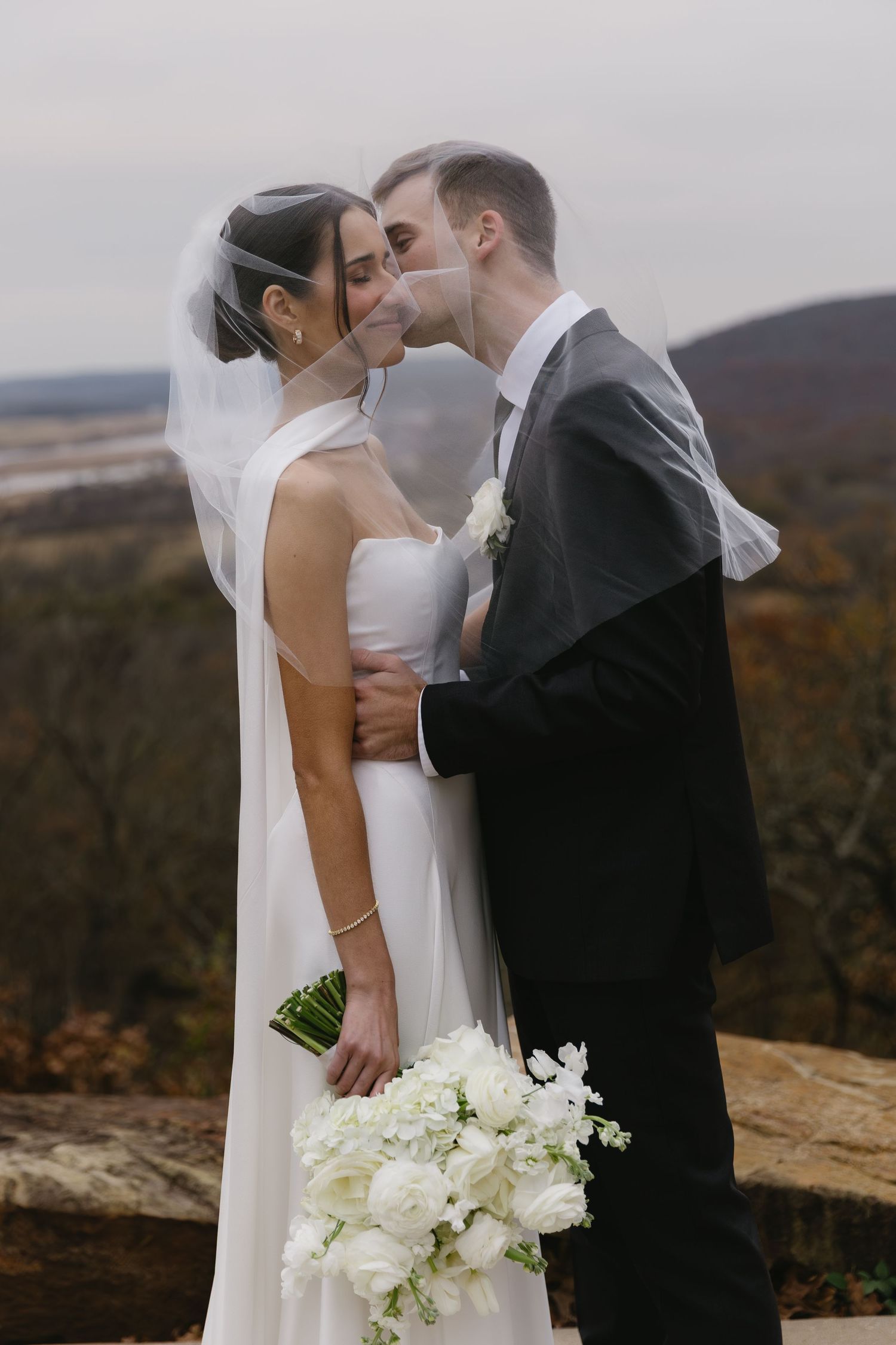 Intimate wedding moment captured on scenic overlook during autumn season.