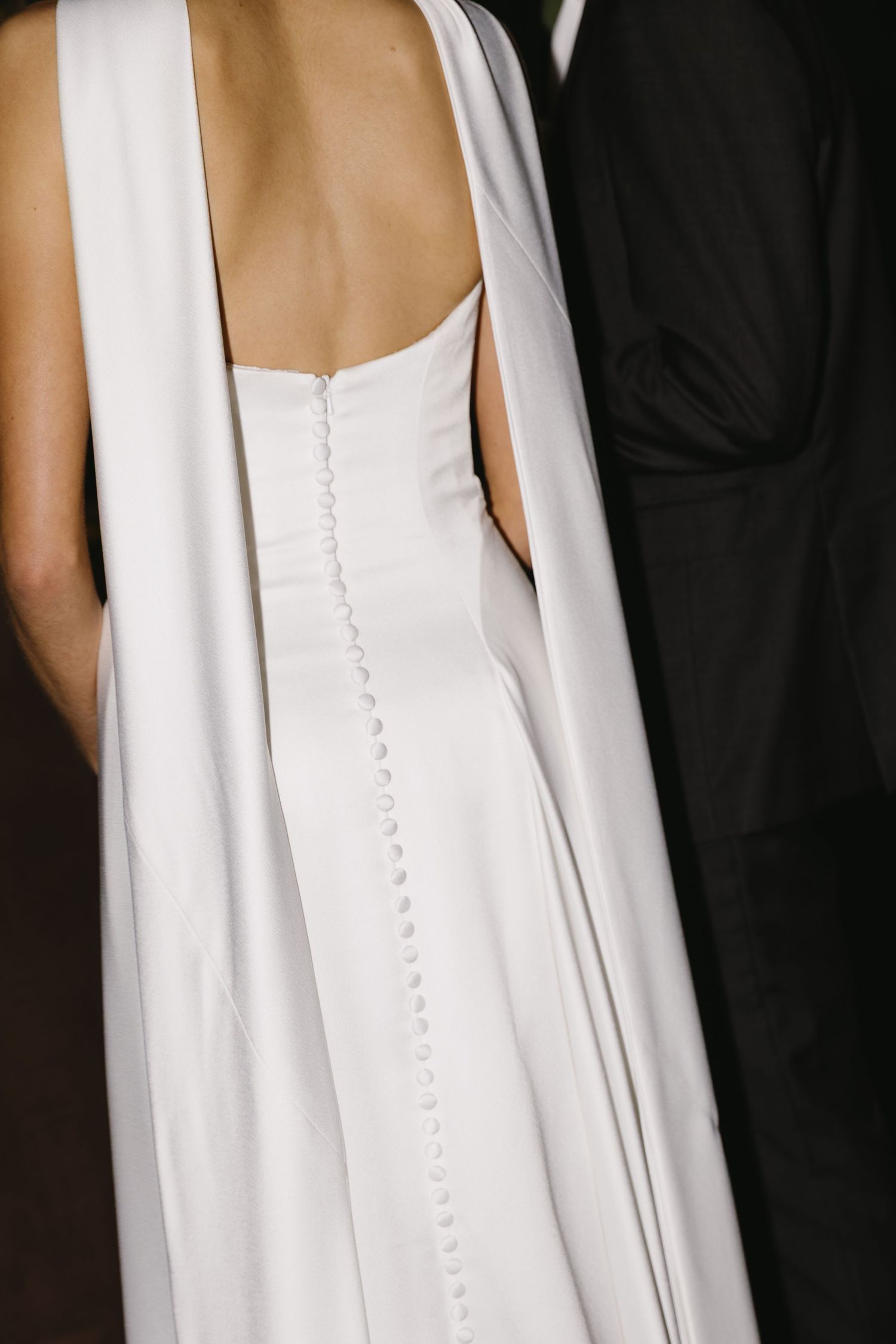 Close-up details of a white wedding dress showing delicate button closures down the back.
