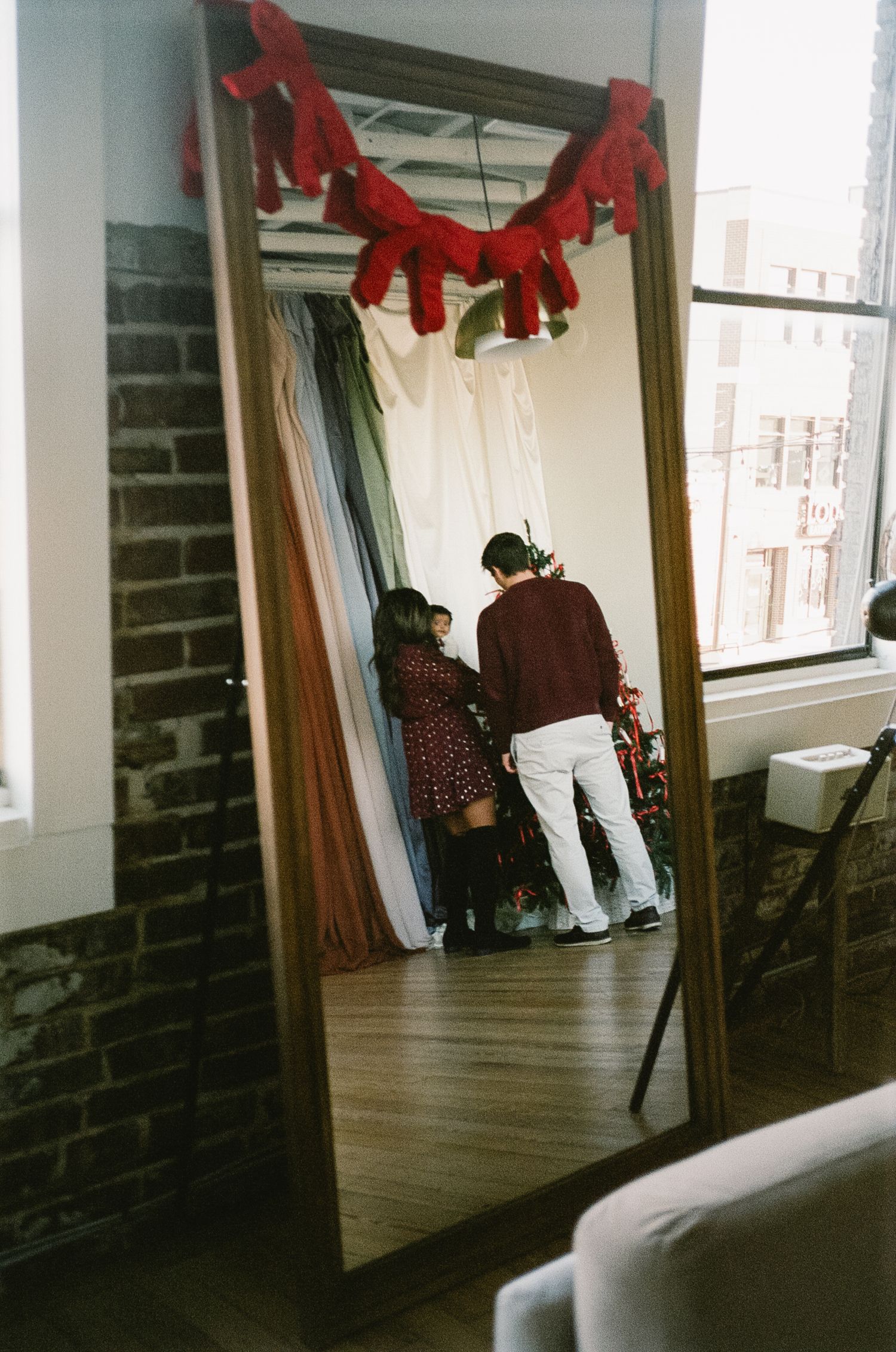 Behind-the-scenes view of a holiday photoshoot with red decorations and brick walls.