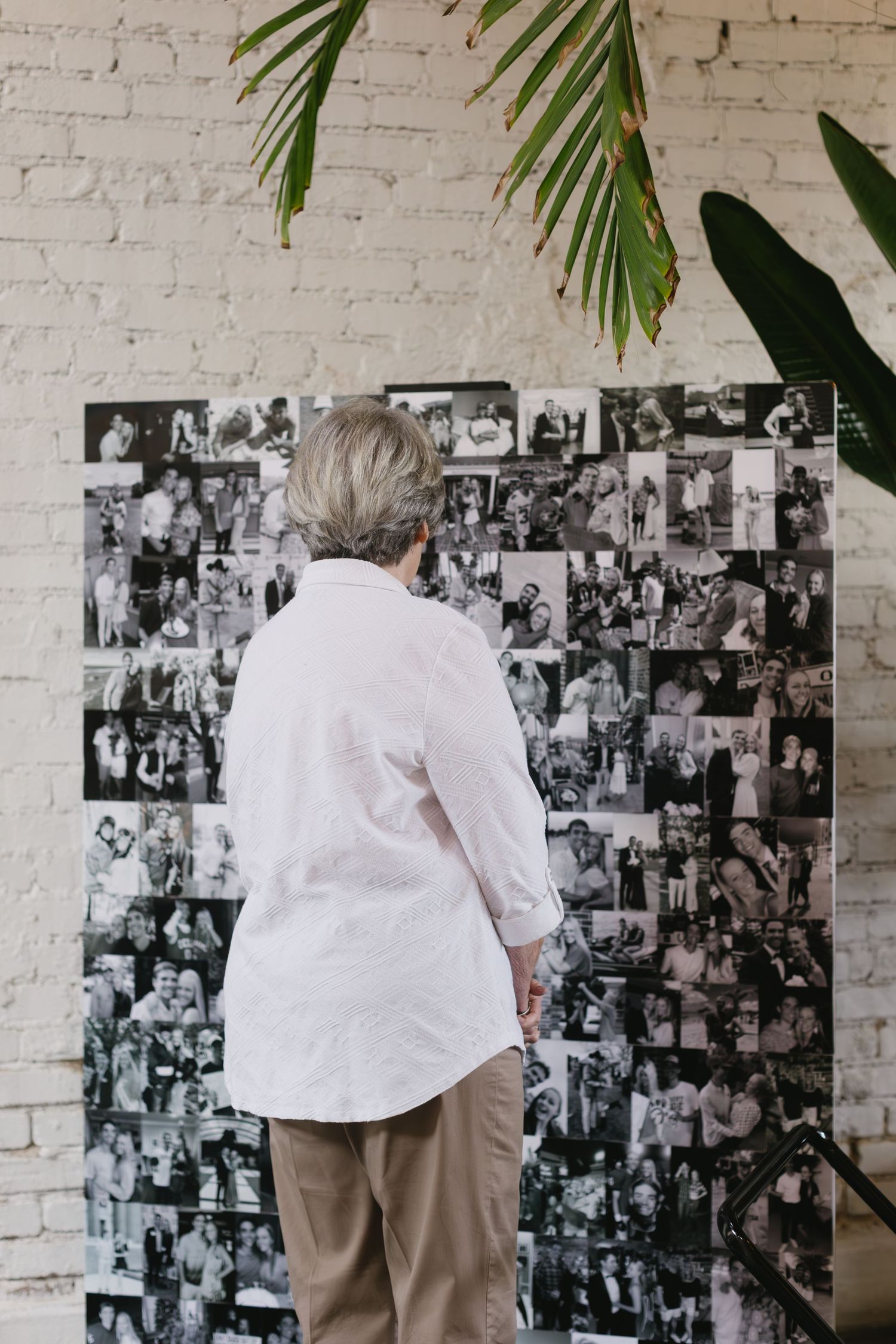 A wall decorated with black and white photos serves as backdrop for guests at a special event.