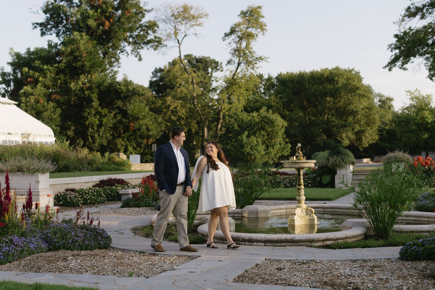 Wide landscape view of a garden setting with couples walking in the distance during golden hour.