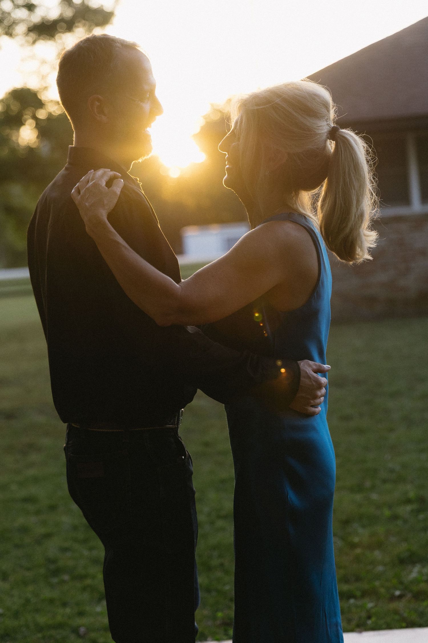 Silhouetted couple dancing at sunset during an outdoor celebration.
