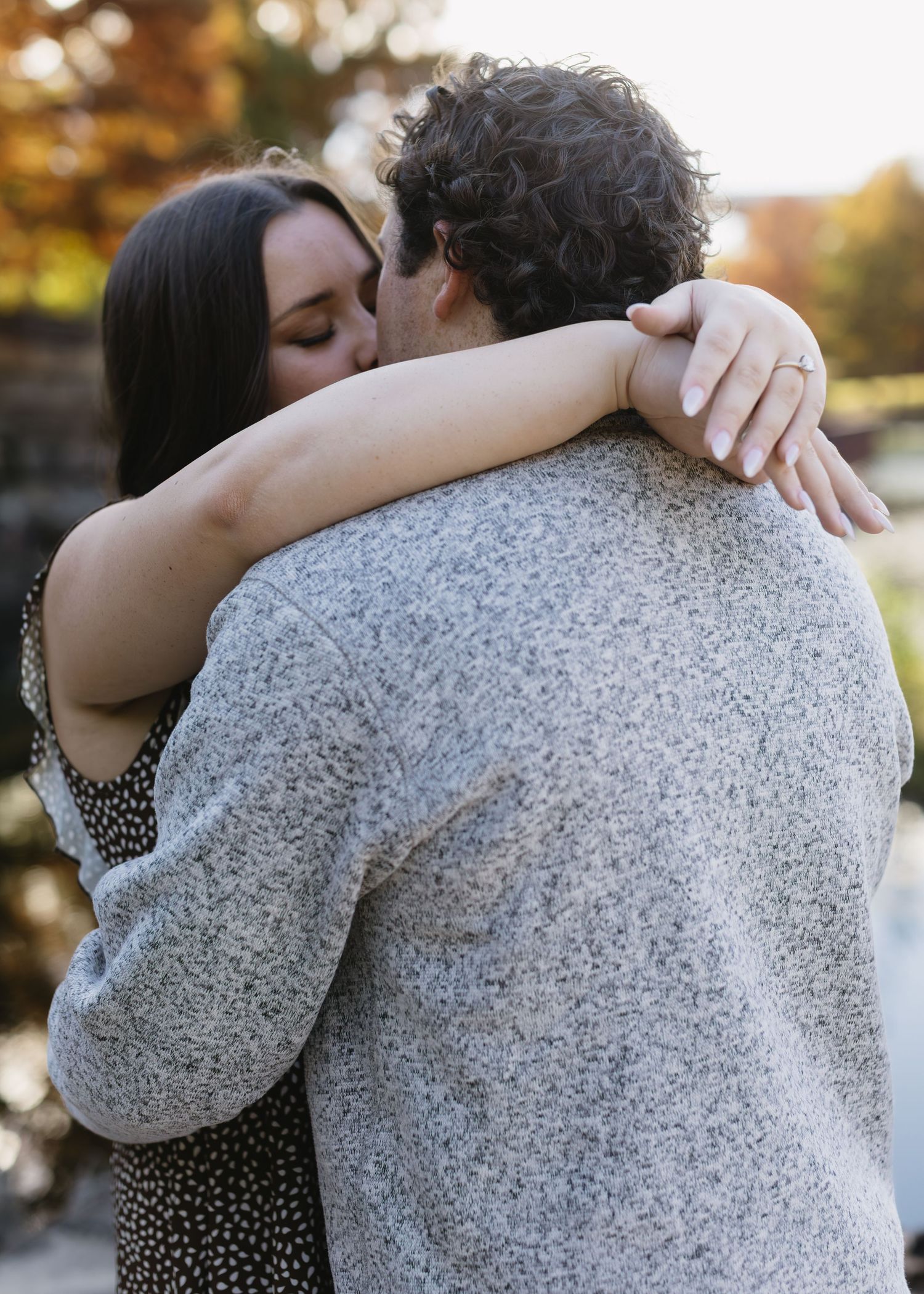 A couple embracing during sunset with autumn colors in the background.