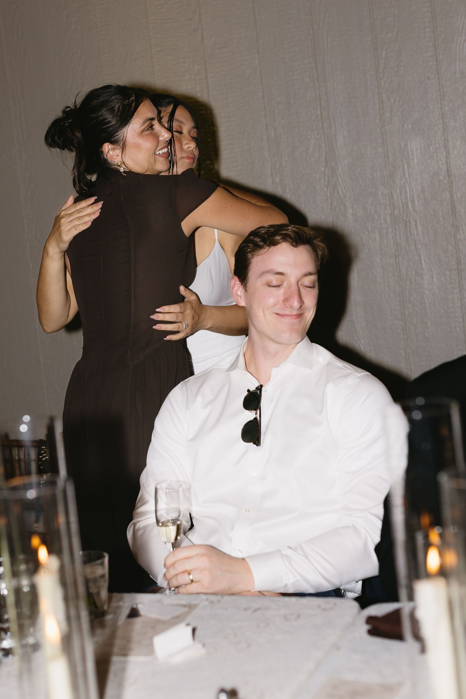 Wedding reception candlelit scene with guests enjoying intimate moments at dinner.