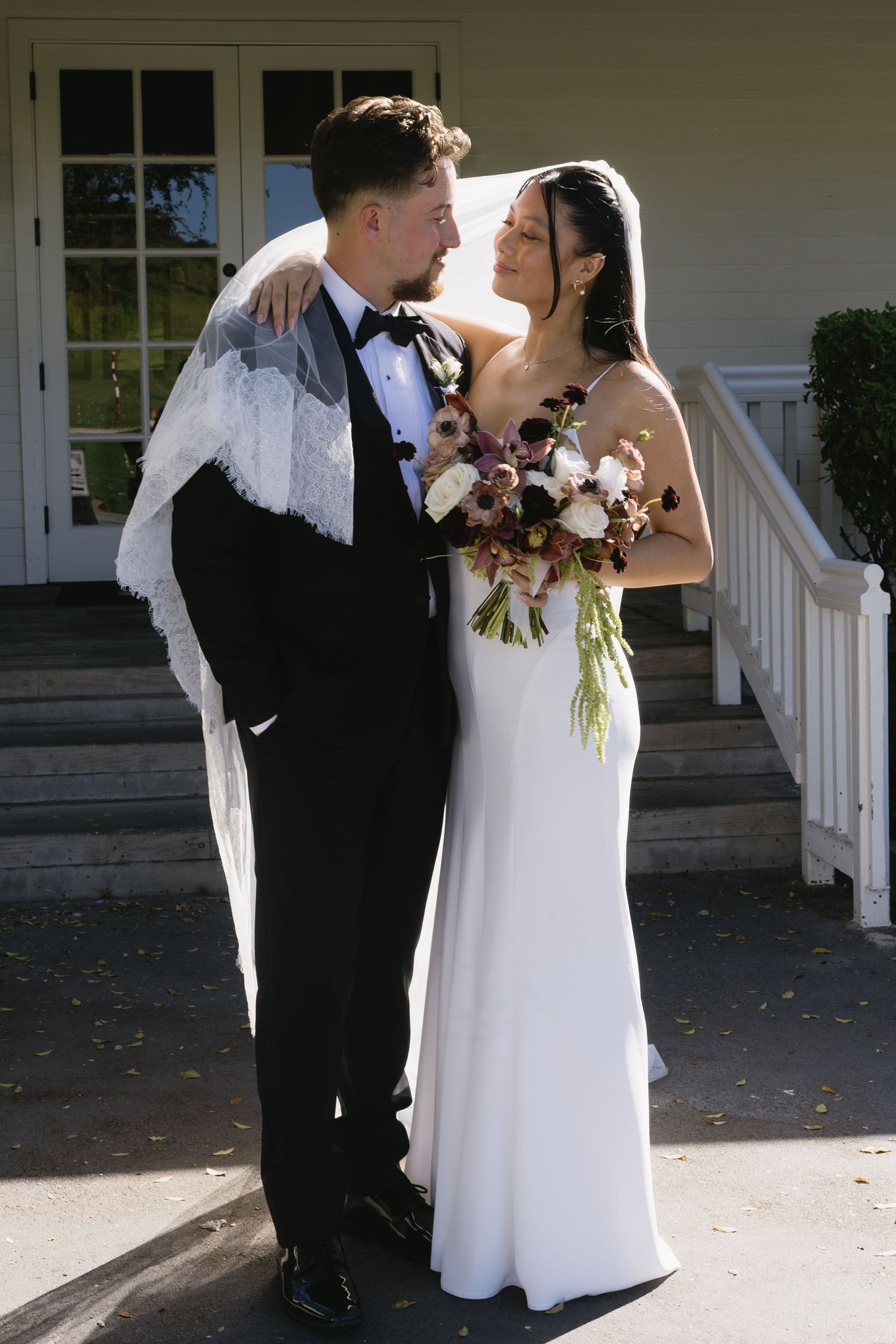 Bride and groom share intimate moments outside white building with pillars.