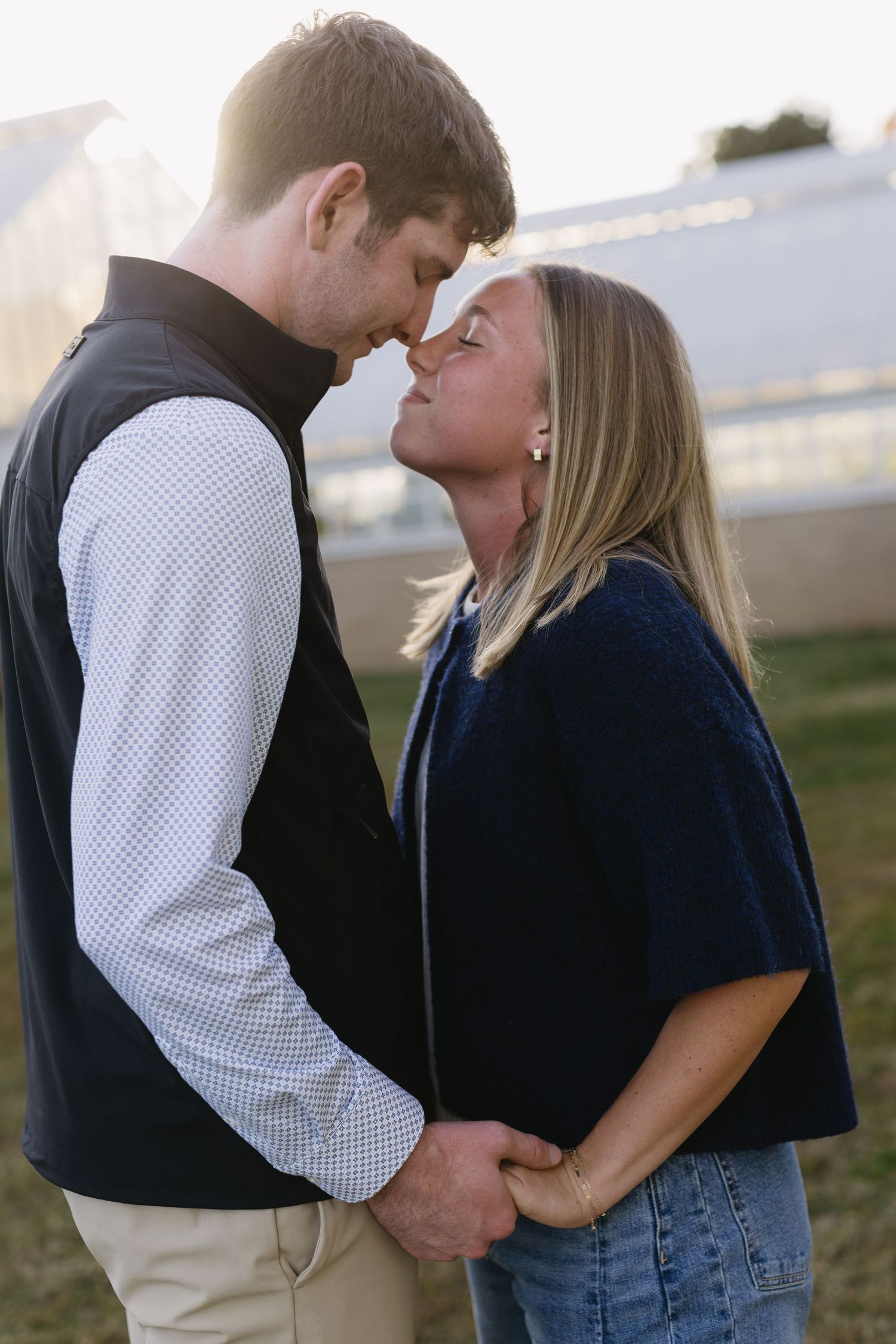 Couple in casual attire sharing an intimate moment outdoors at sunset.