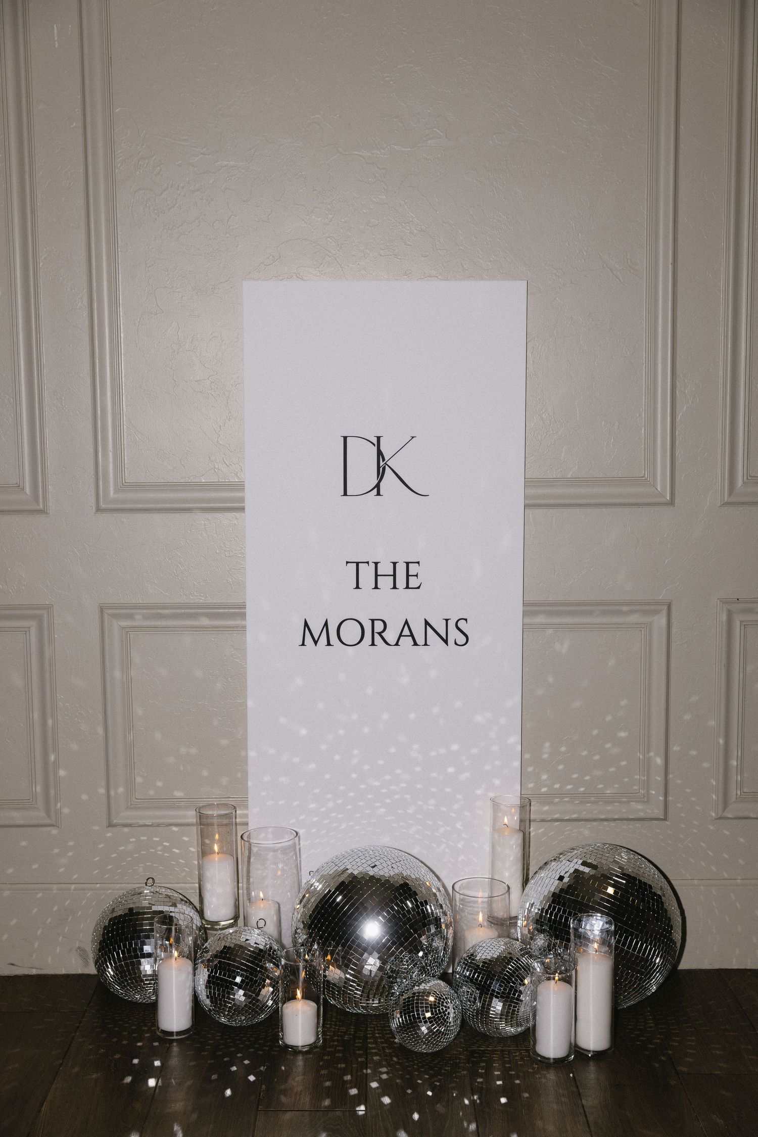 Wedding reception decor featuring DK monogram sign with disco balls and candles.