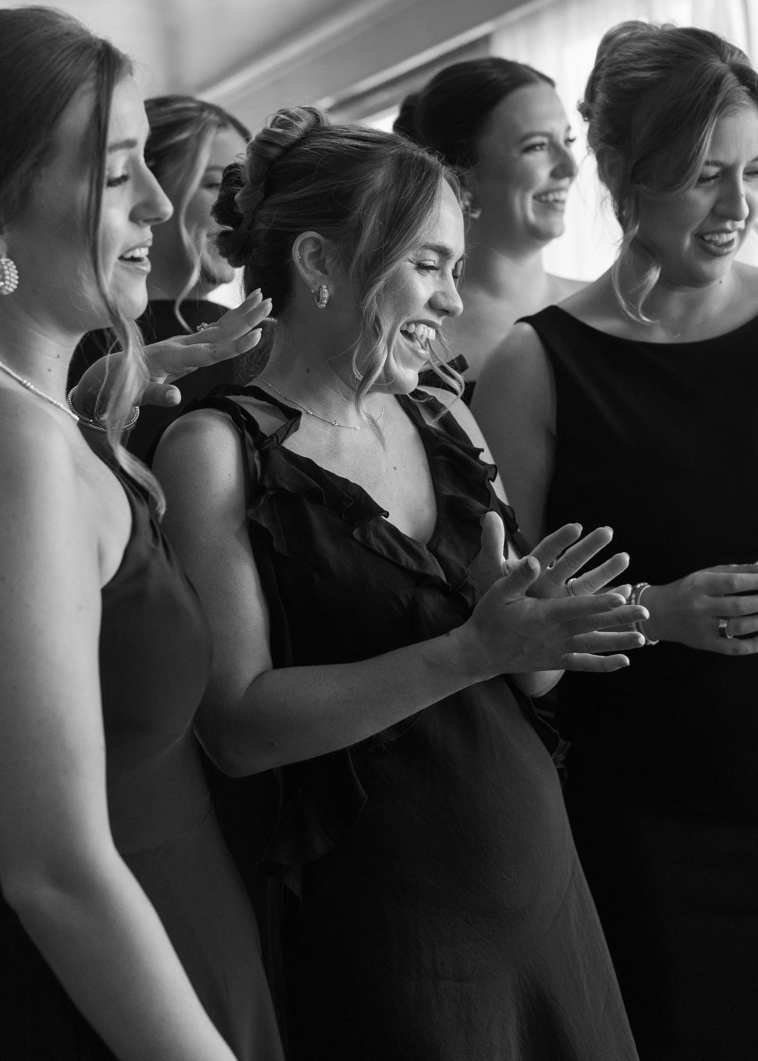 Black and white photo of wedding party sharing a joyful moment.