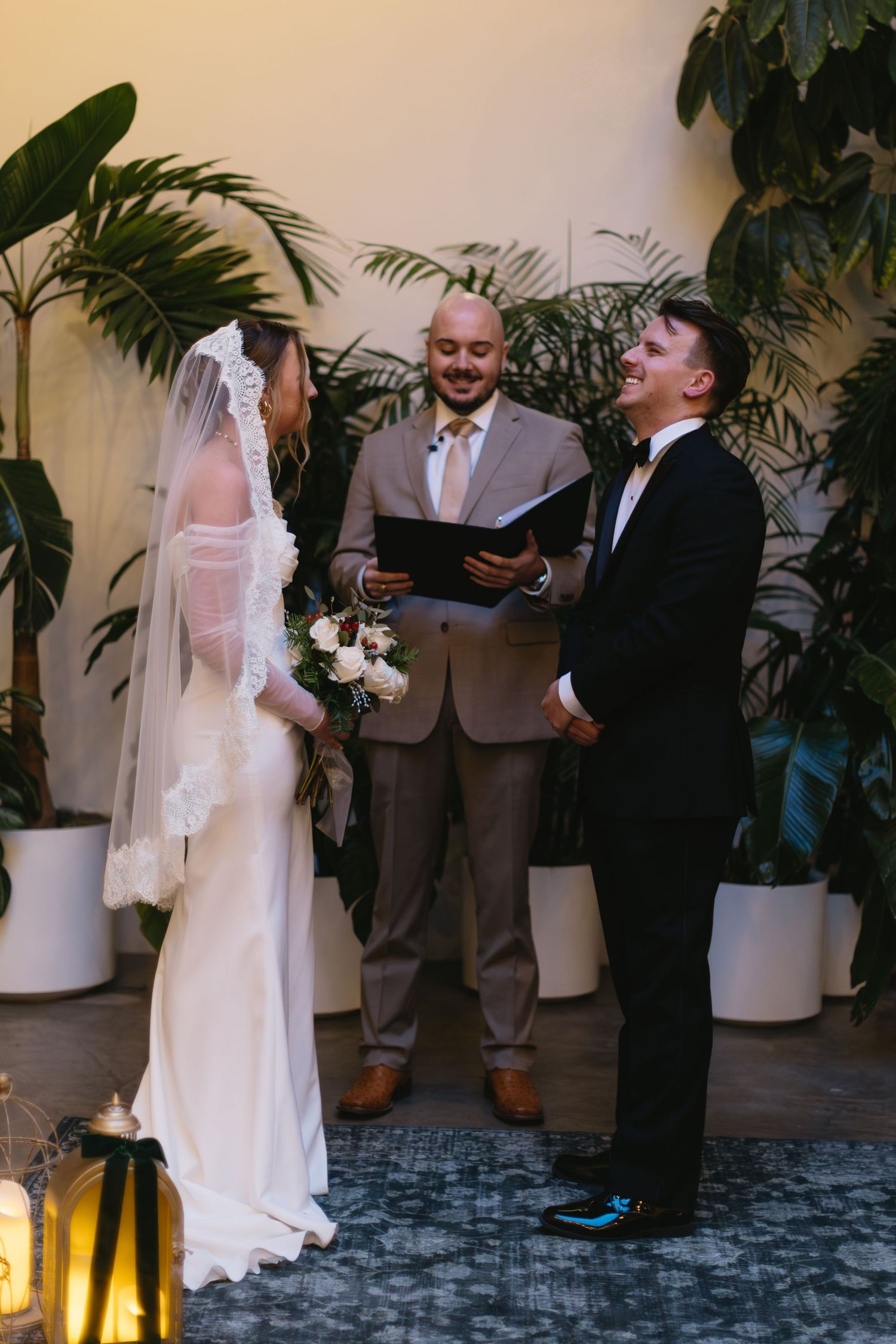 Wedding ceremony in progress with tropical plants and lanterns decorating the space.