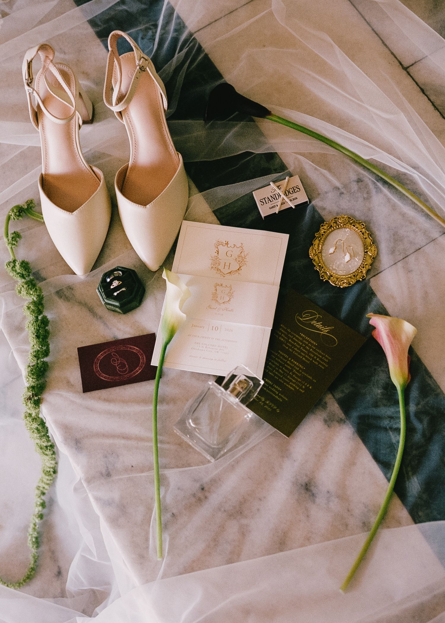 Wedding details flatlay with ivory heels, invitations, and delicate floral stems.