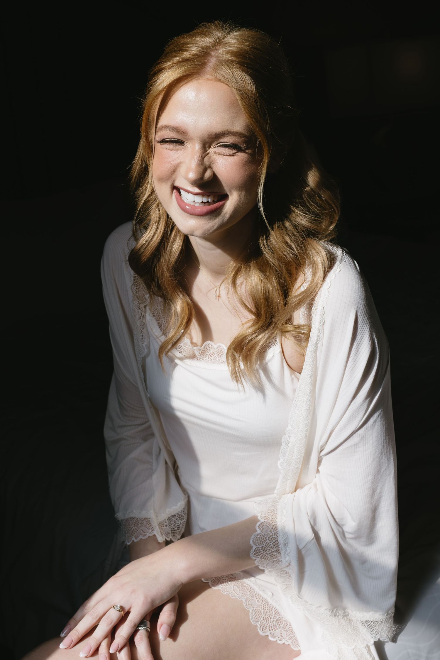 Soft natural light illuminates a white silk robe against a dark background.