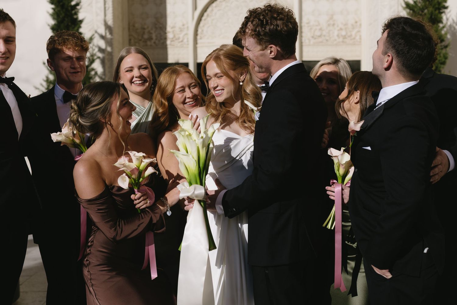 Wedding party members interact playfully during outdoor photo session.
