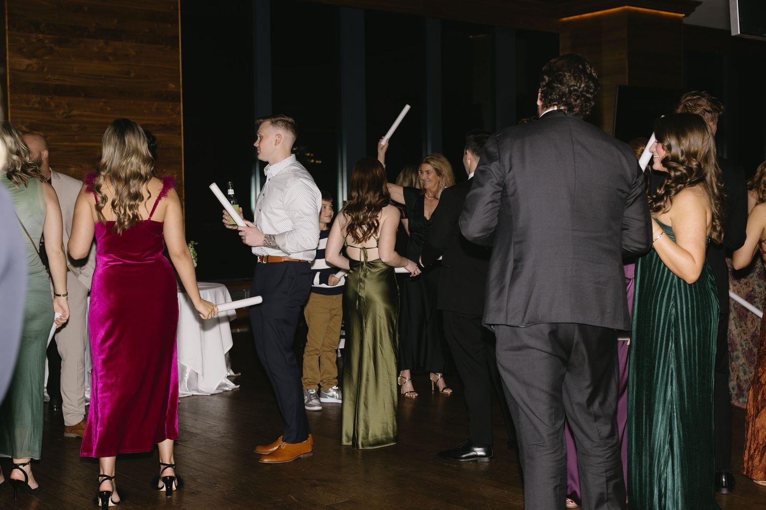 Wedding guests dancing and celebrating at evening reception with colorful formal attire.