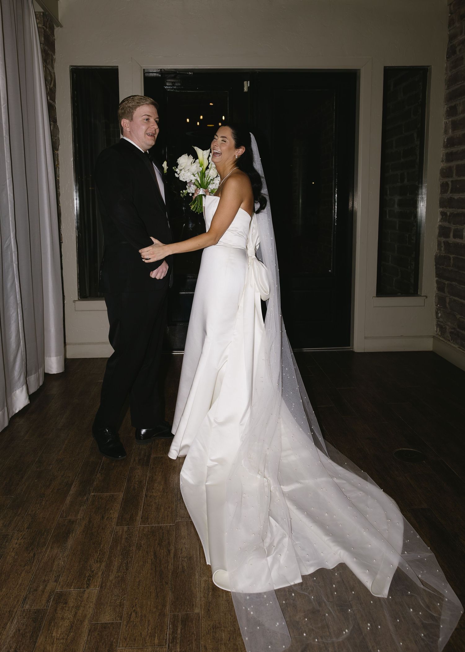 Wedding couple dancing together in an indoor venue with flowing white dress and veil.