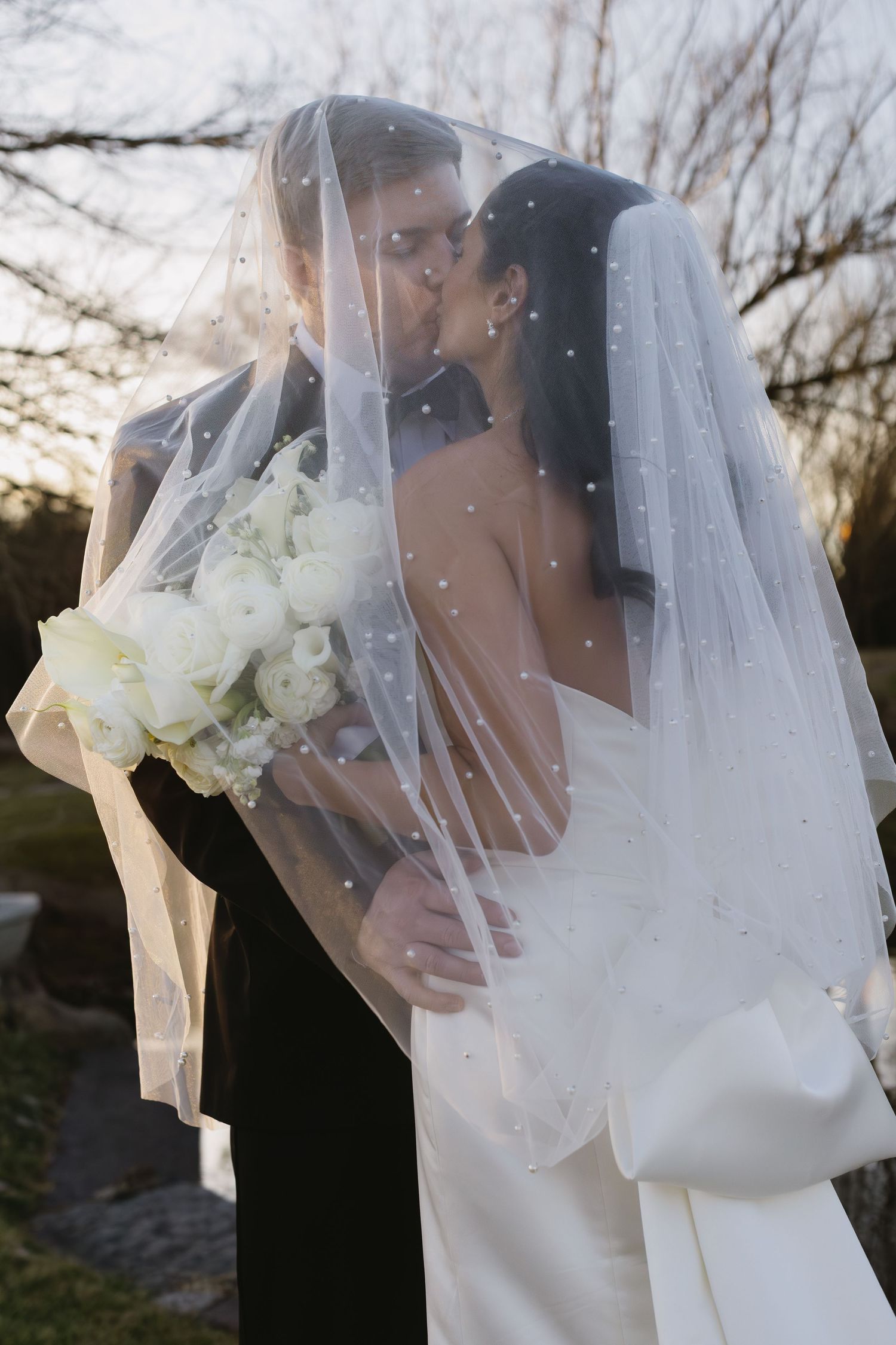 Elegant bridal details featuring white veil and roses in natural light.