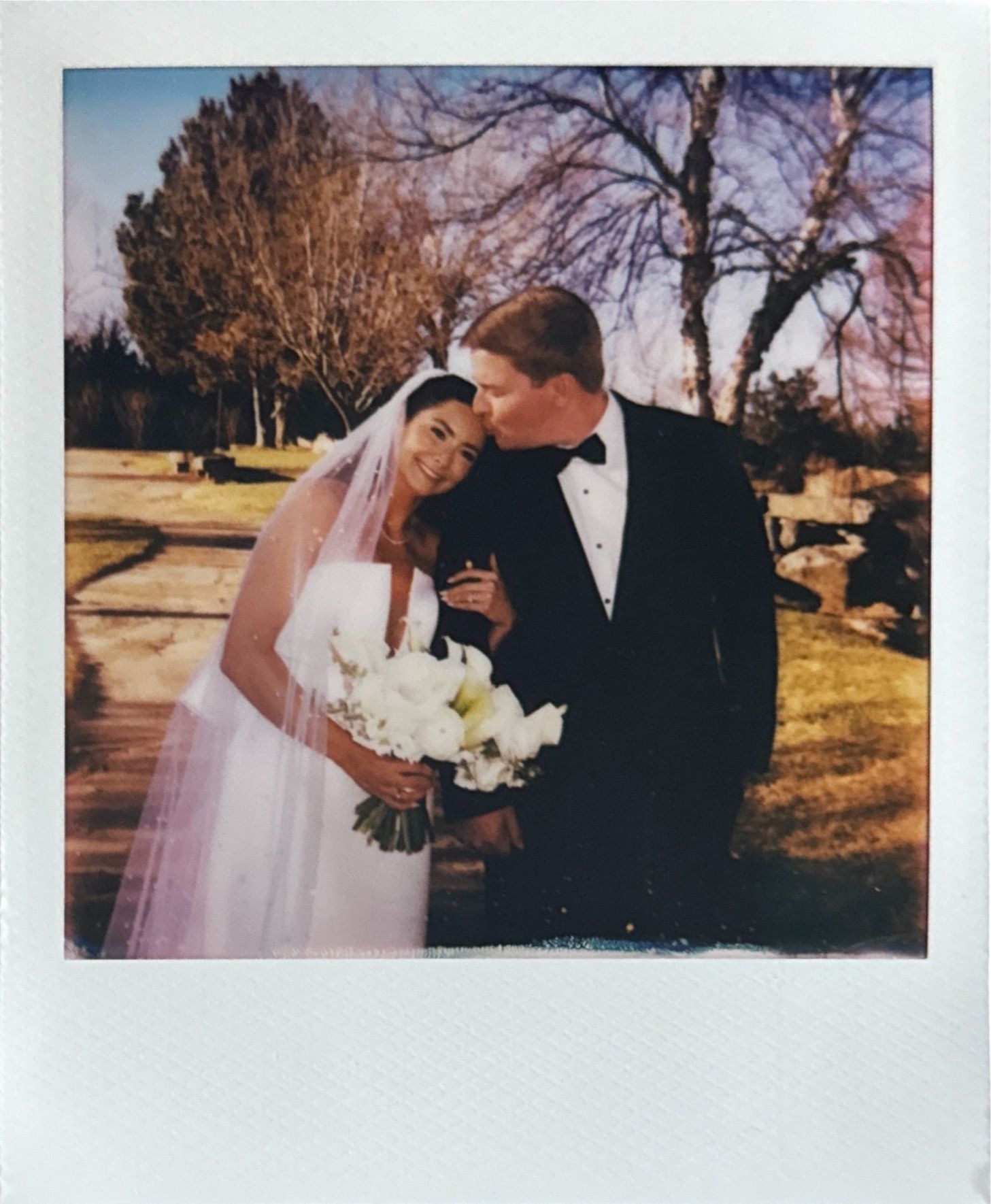 Vintage-style polaroid wedding photo taken outdoors during sunset.