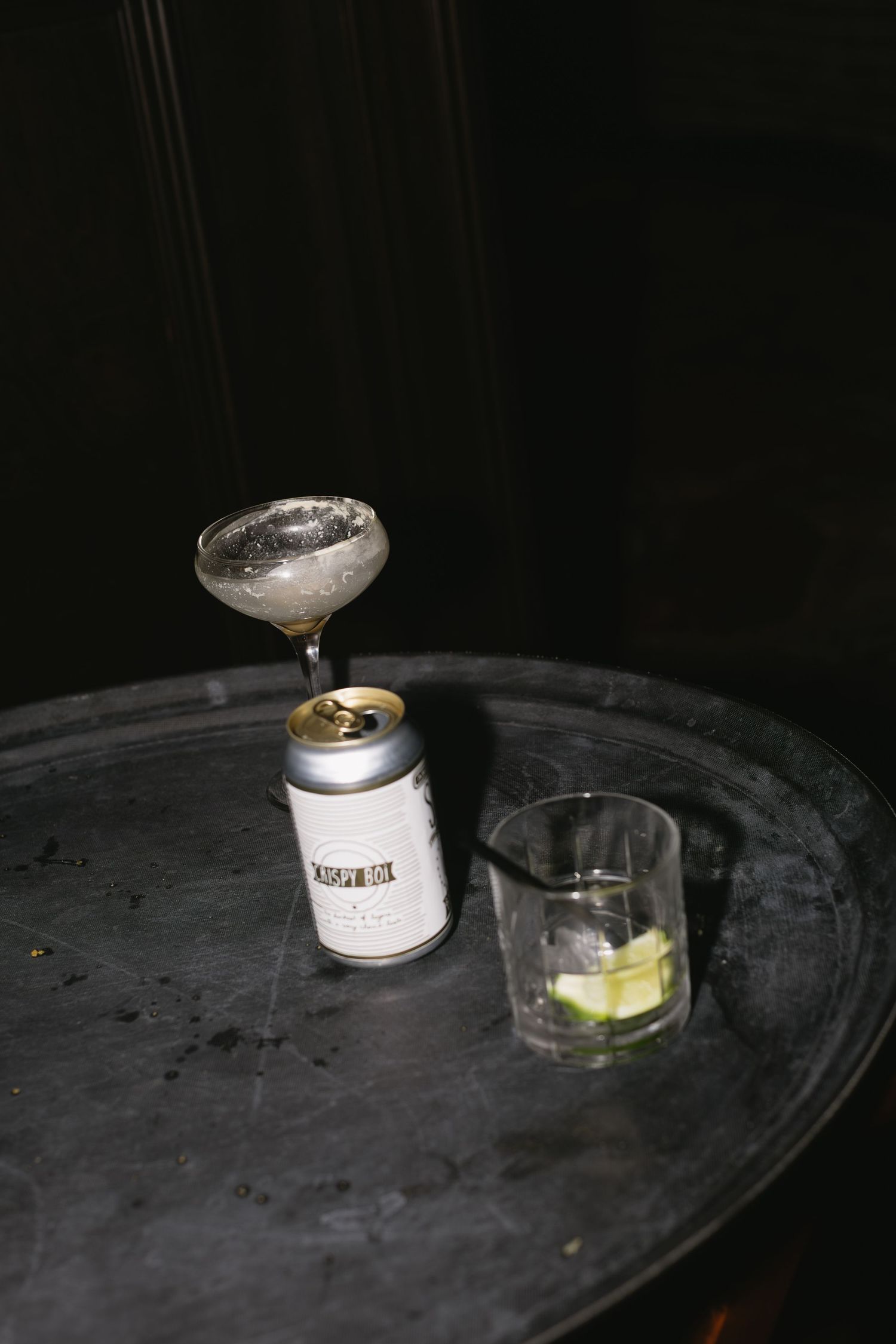 Dark moody photo of cocktail ingredients and garnishes on a black surface.