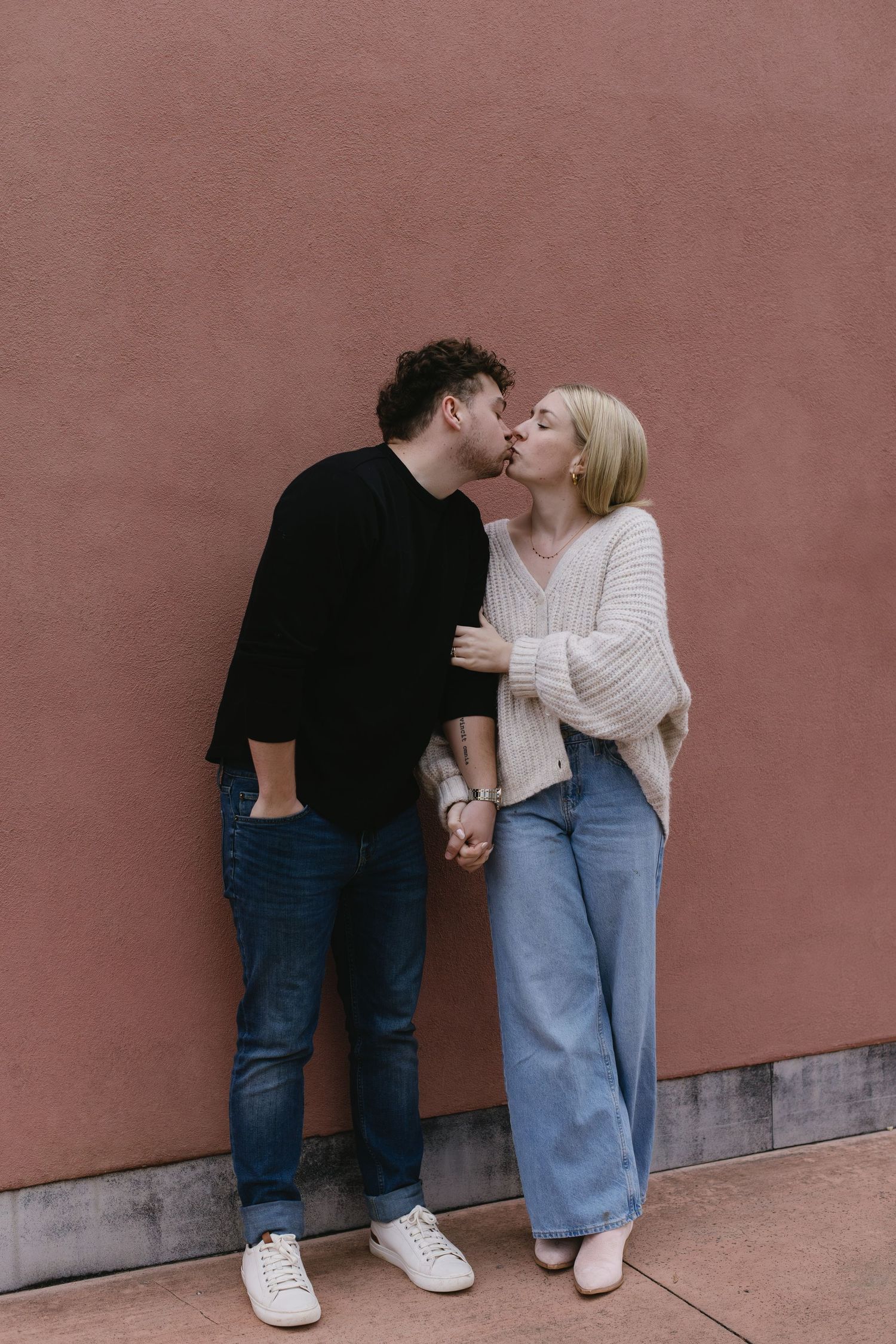 A romantic moment against a rustic red wall.