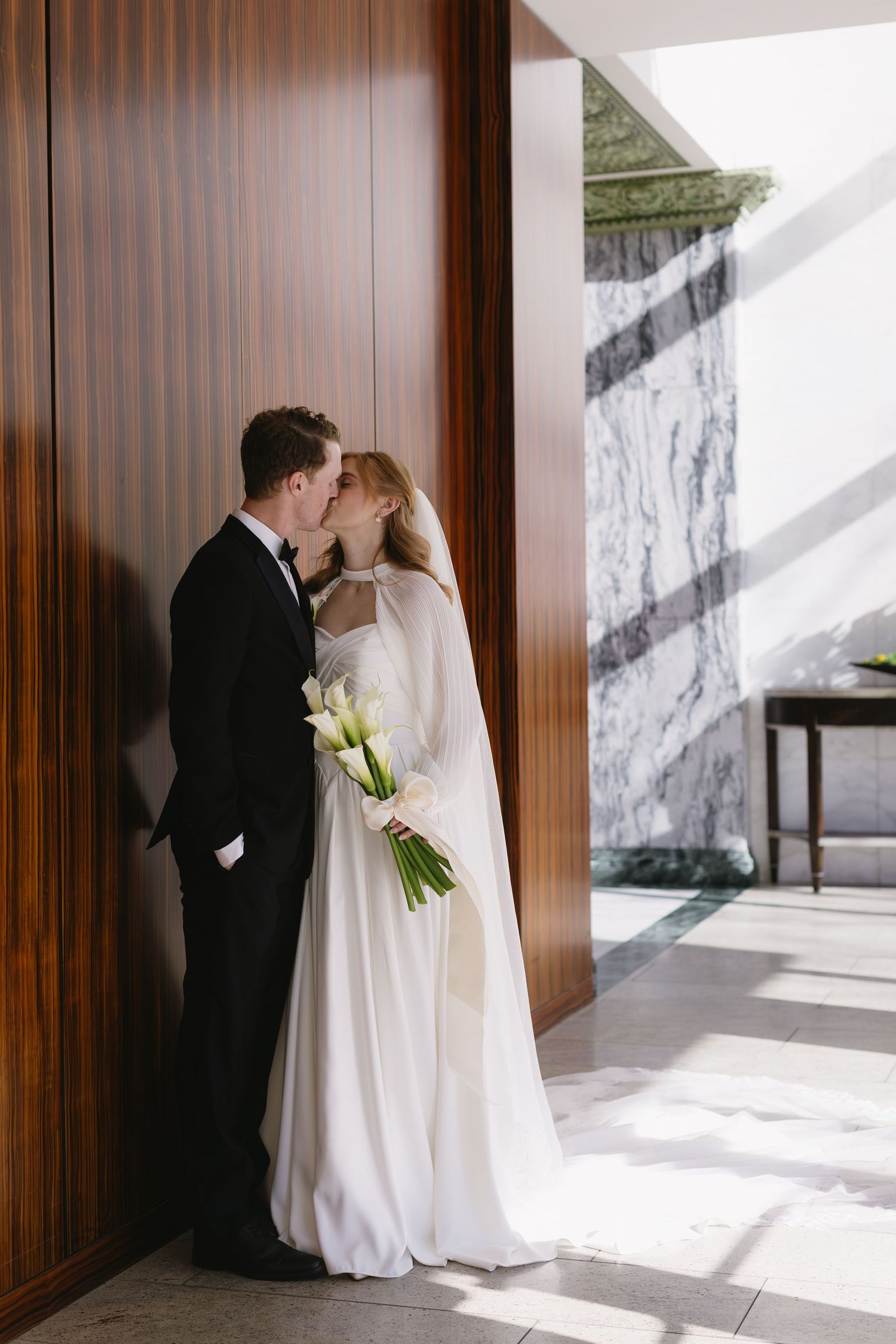 Intimate wedding portraits against wooden panels with dramatic natural lighting.