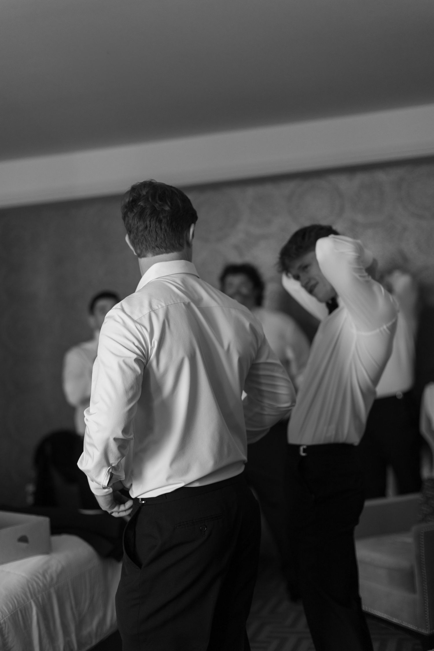 Black and white photo showing two men in formal attire getting dressed in a room.