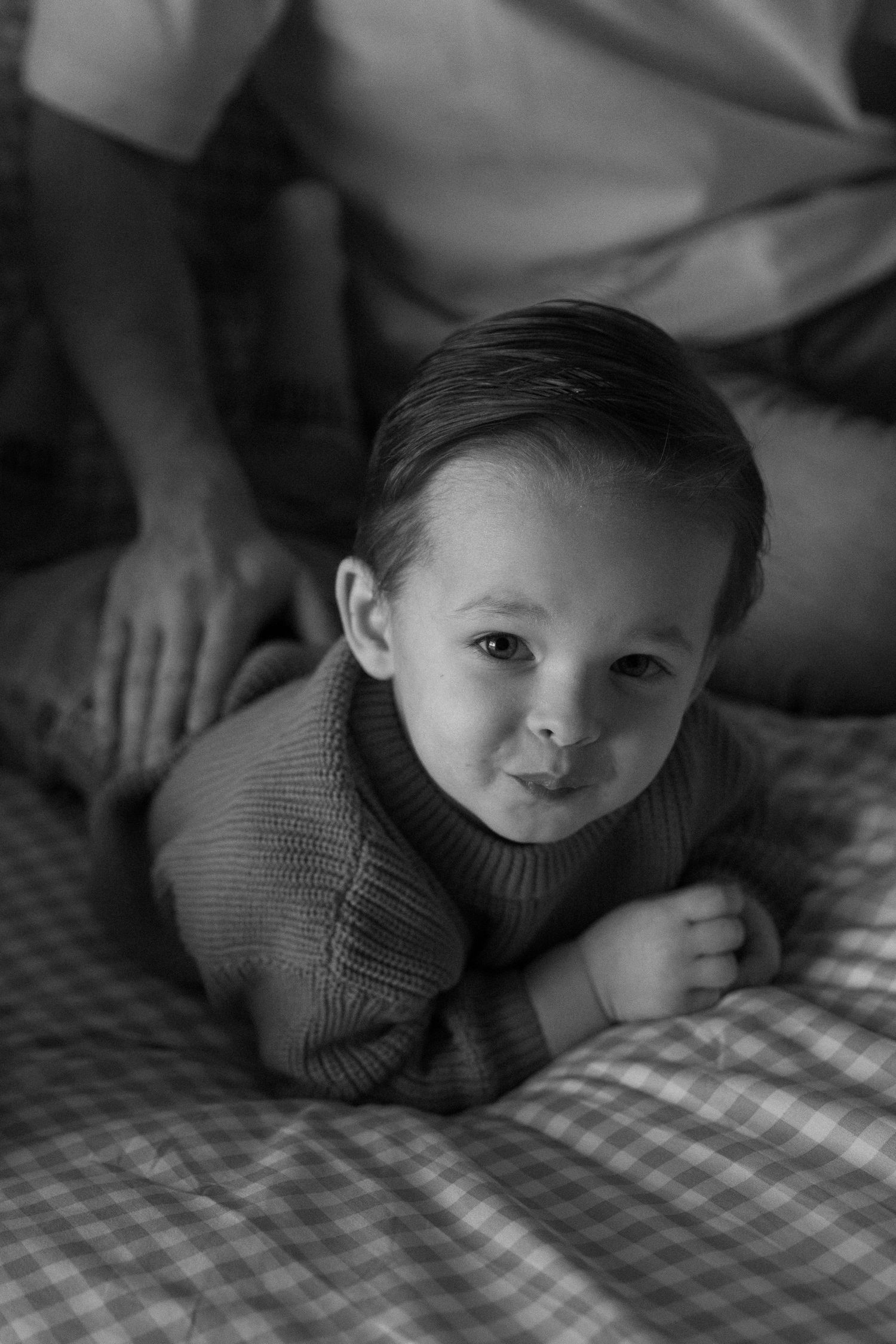 Black and white series of a baby lying on checkered bedding making expressive faces.