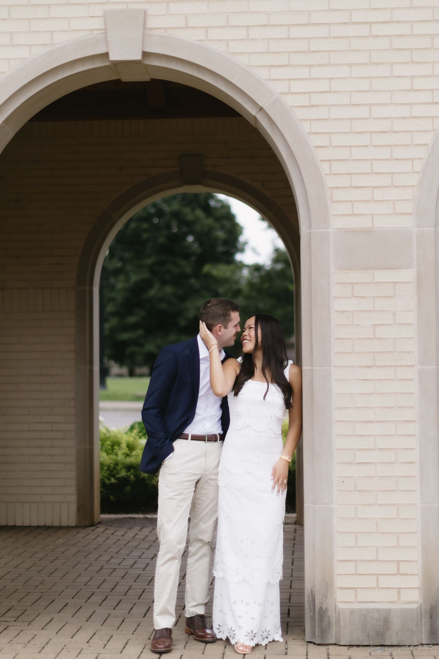 A couple shares intimate moments under white brick archways during their wedding photo session.