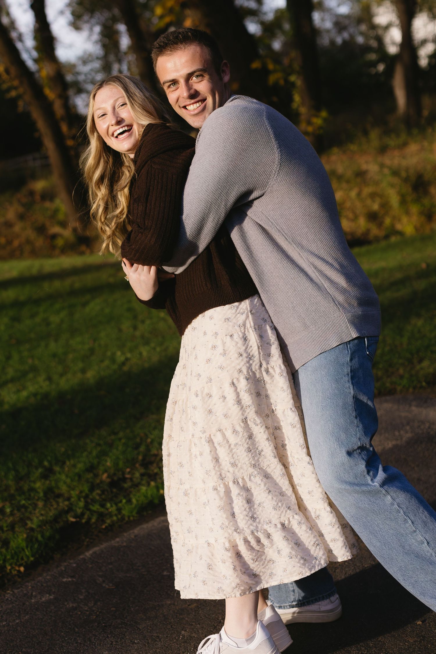 A couple shares joyful moments together during golden hour in a park setting.