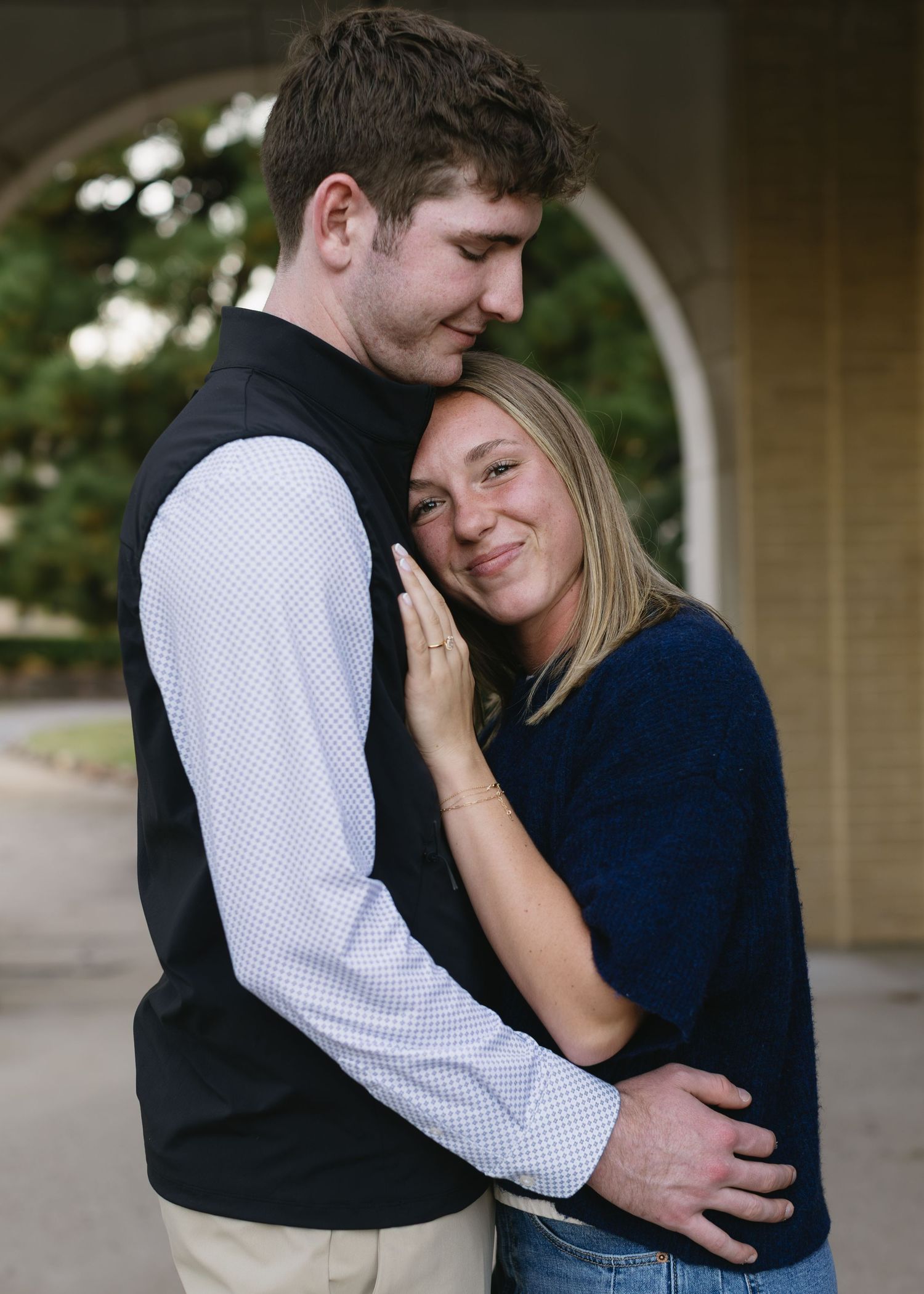 A tender moment between two people in casual attire against a neutral background.