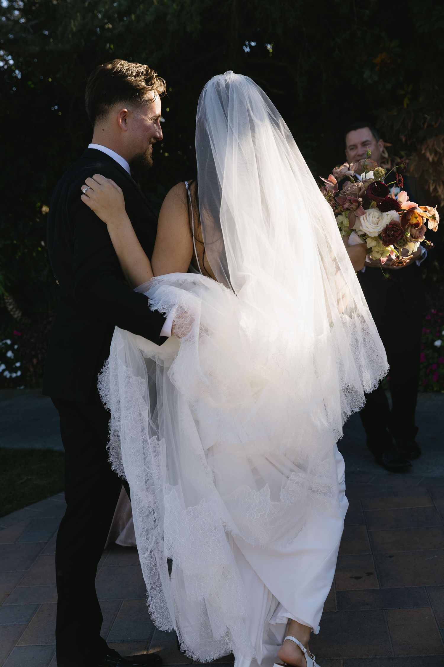 A couple shares an intimate dance moment at their wedding, with the bride's flowing white veil and dress catching the light.