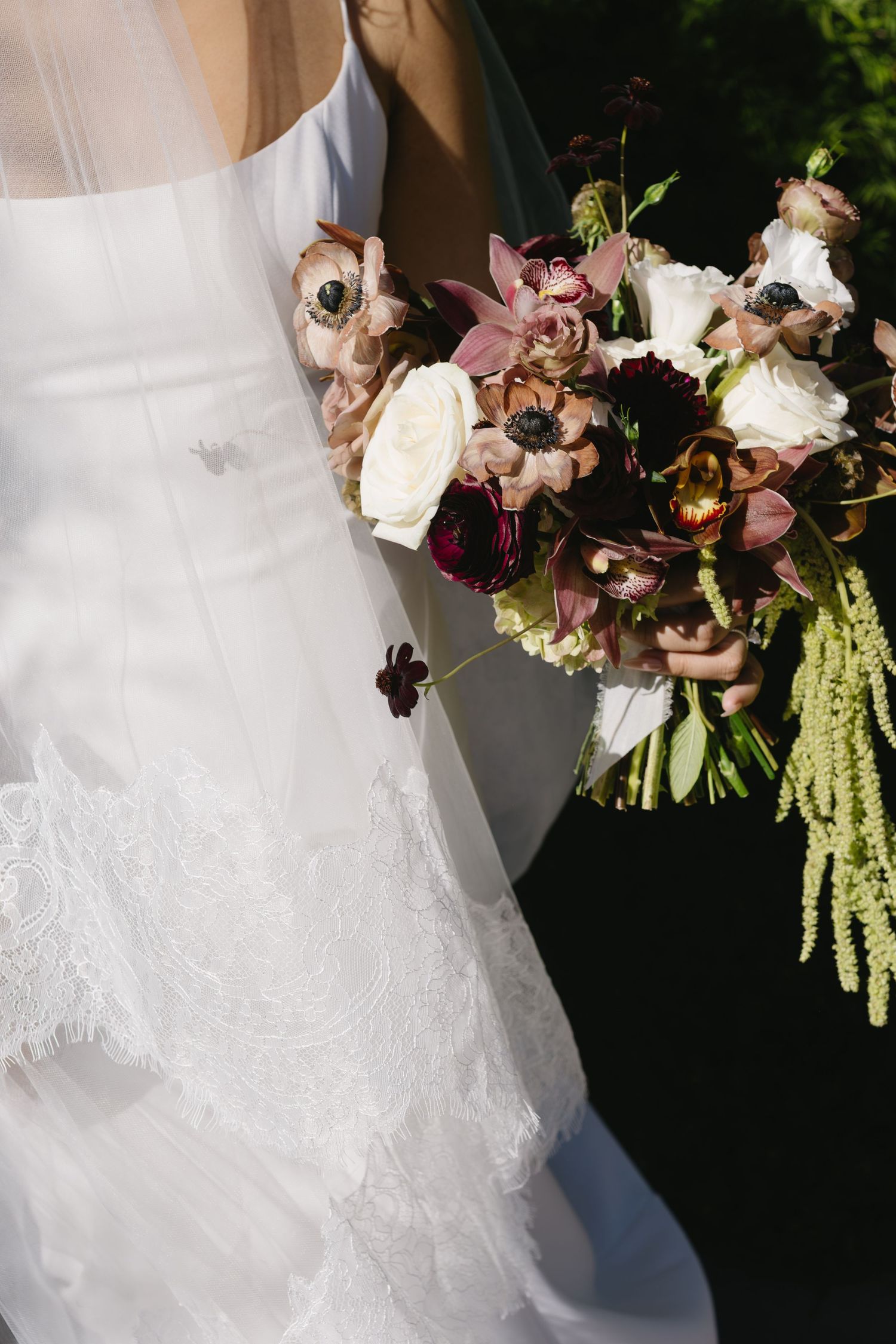Wedding dress details with cascading floral bouquet featuring pink and white blooms.
